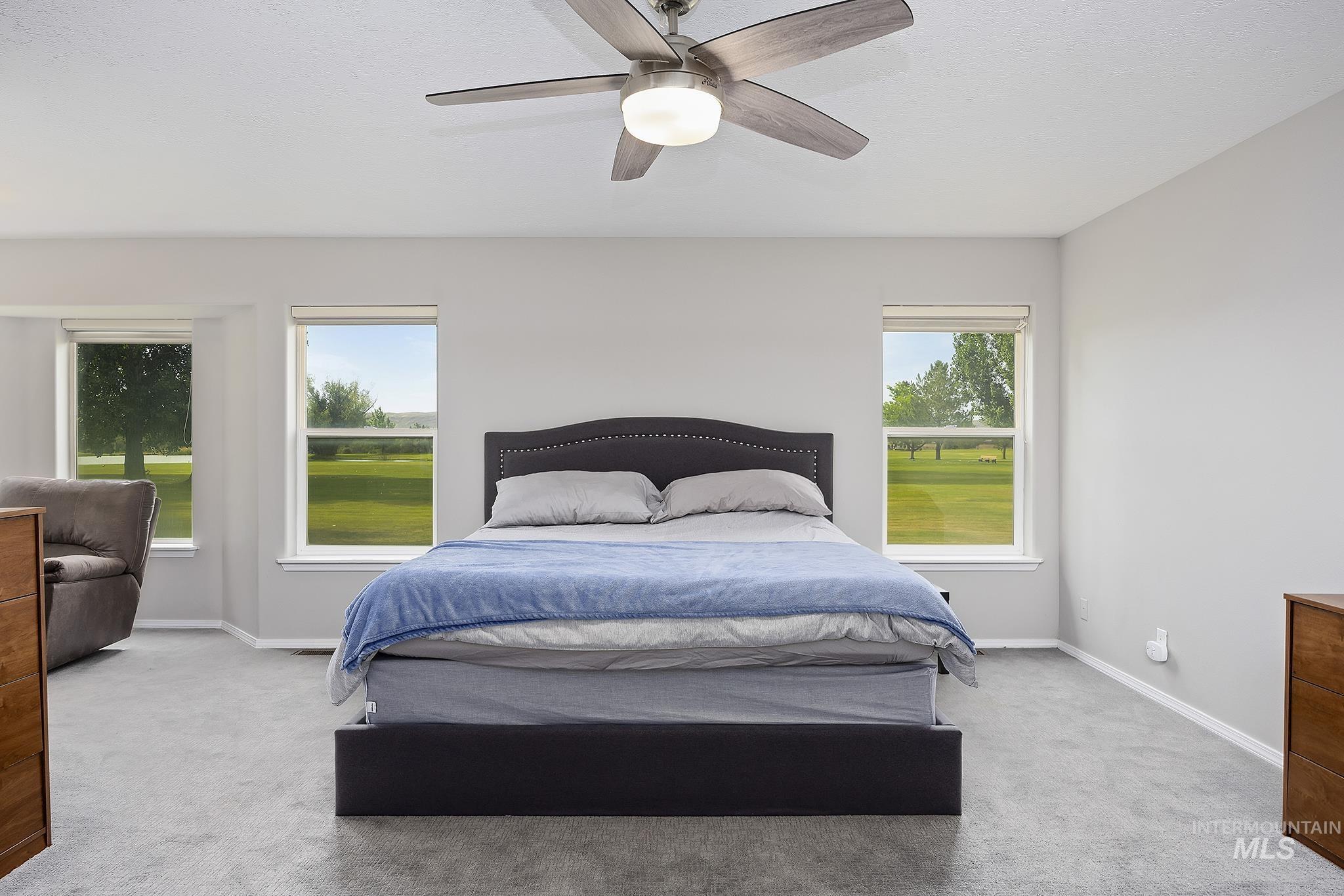 Bedroom with light colored carpet and a ceiling fan