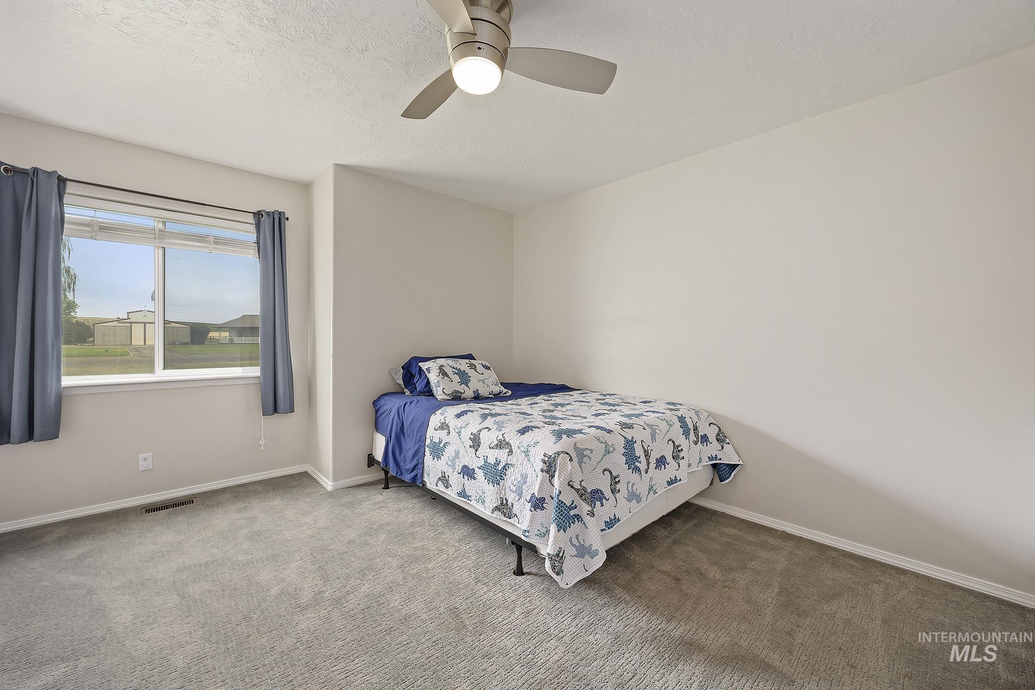 Carpeted bedroom with a ceiling fan and a textured ceiling