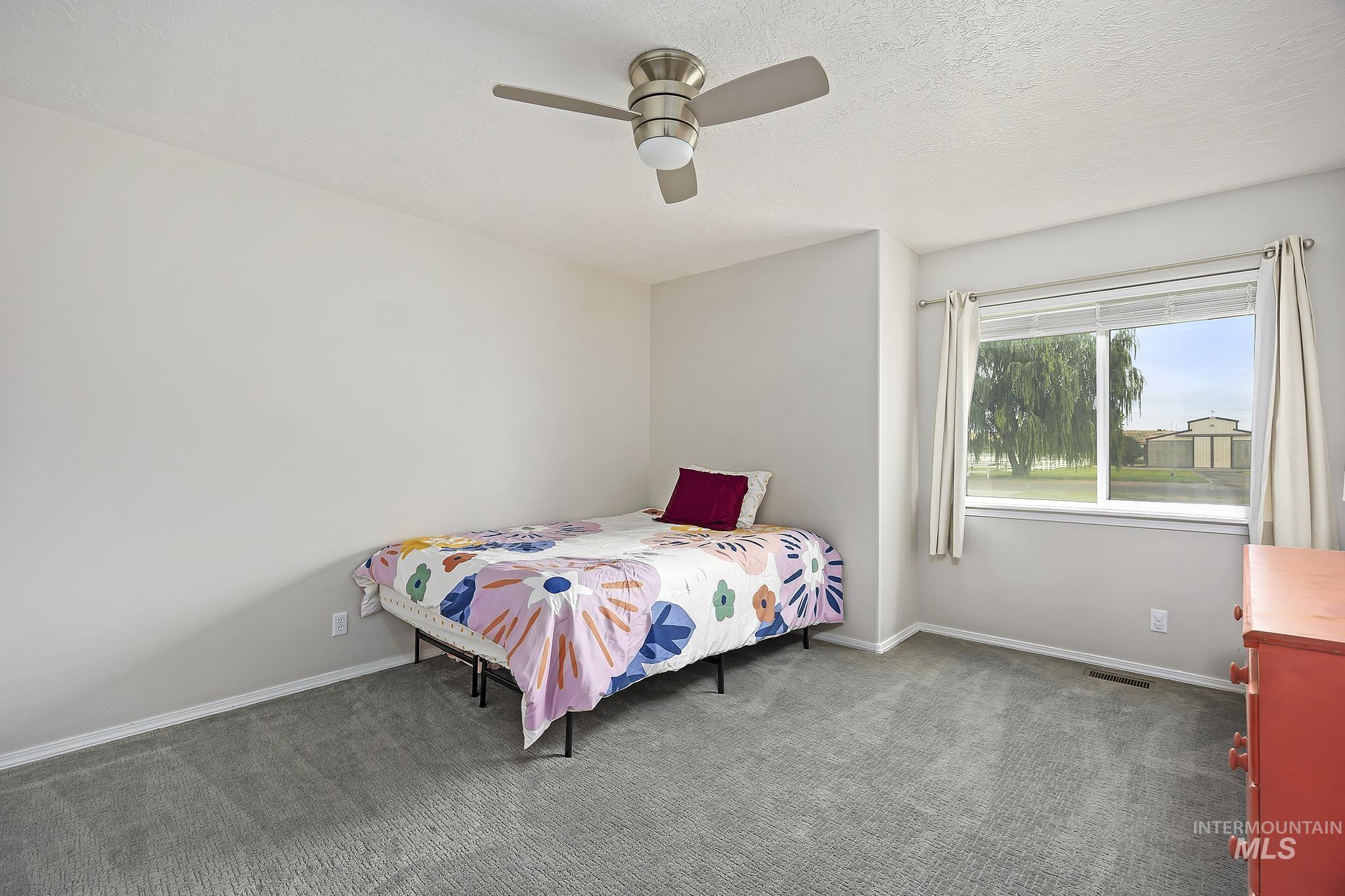 Carpeted bedroom featuring ceiling fan and a textured ceiling