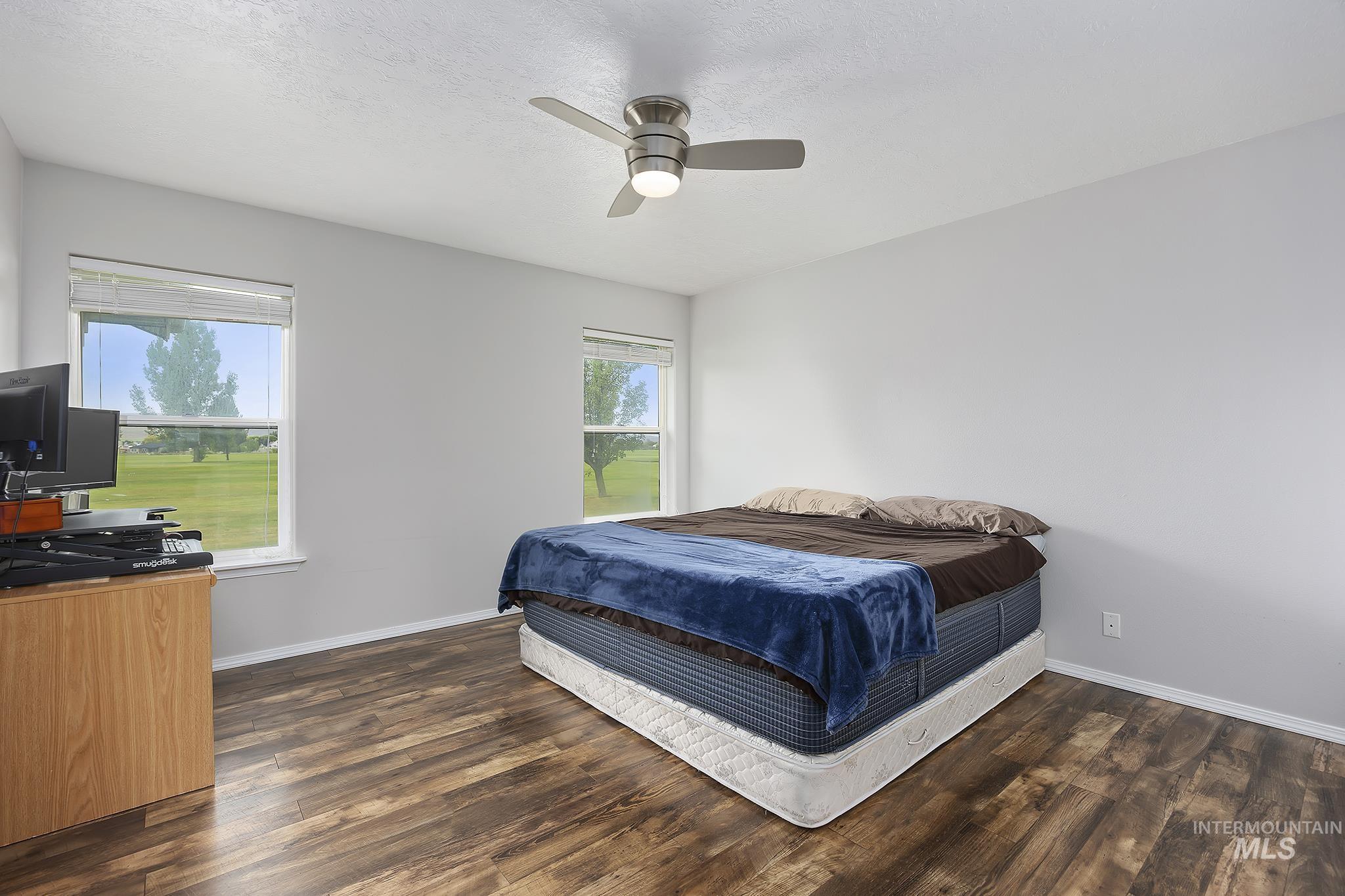 Bedroom featuring multiple windows, a ceiling fan, dark wood-style flooring, and a textured ceiling