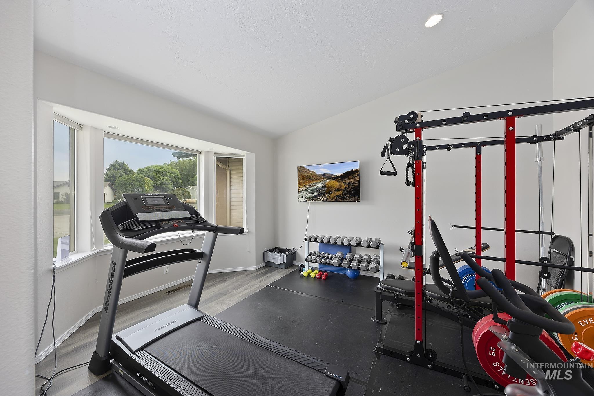 Exercise room with lofted ceiling and wood finished floors