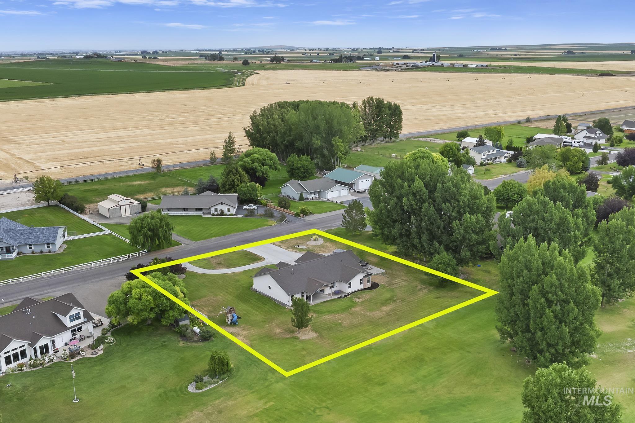 Aerial view of sparsely populated area with property parcel outlined and nearby suburban area