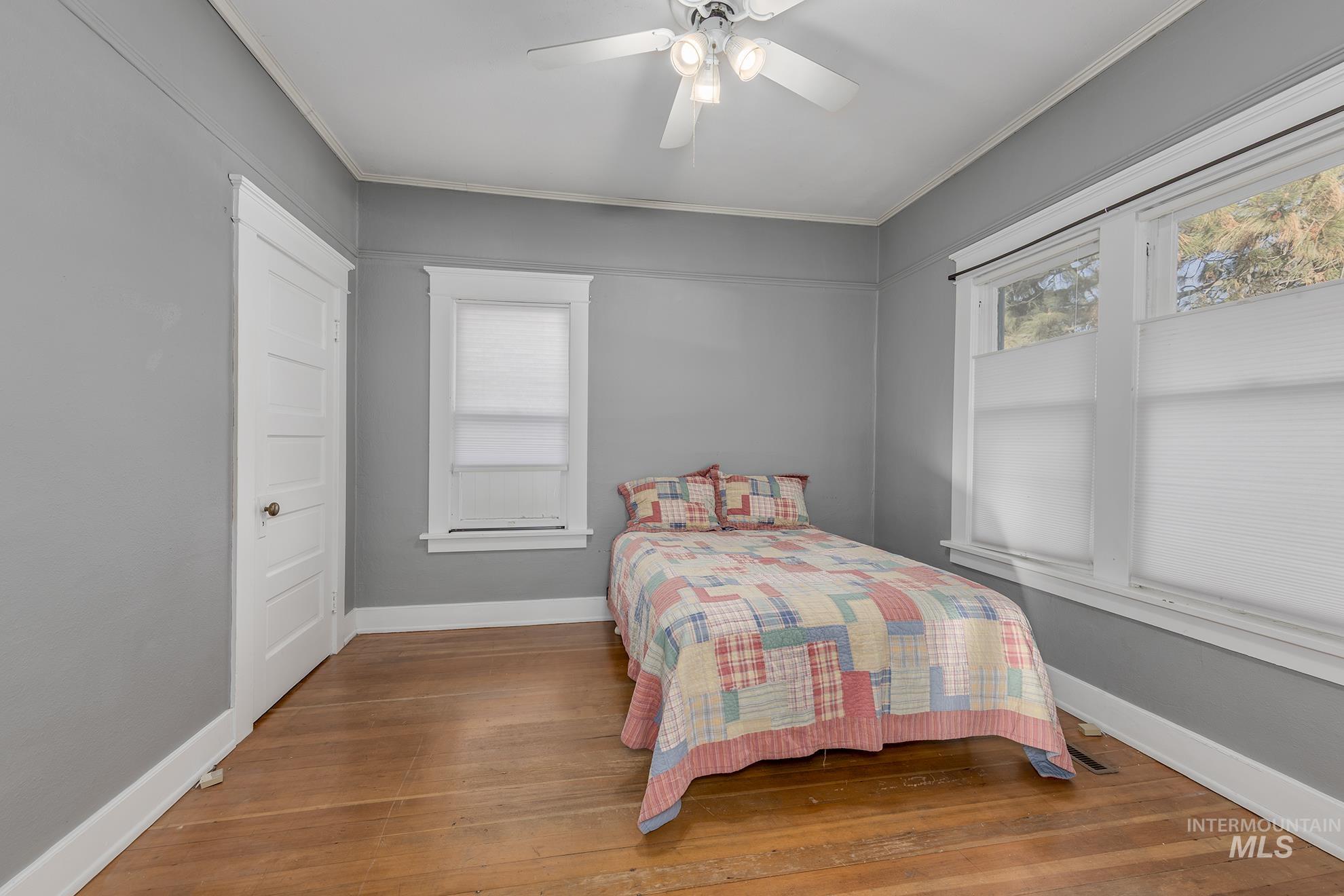 Bedroom featuring hardwood / wood-style flooring, a ceiling fan, and crown molding