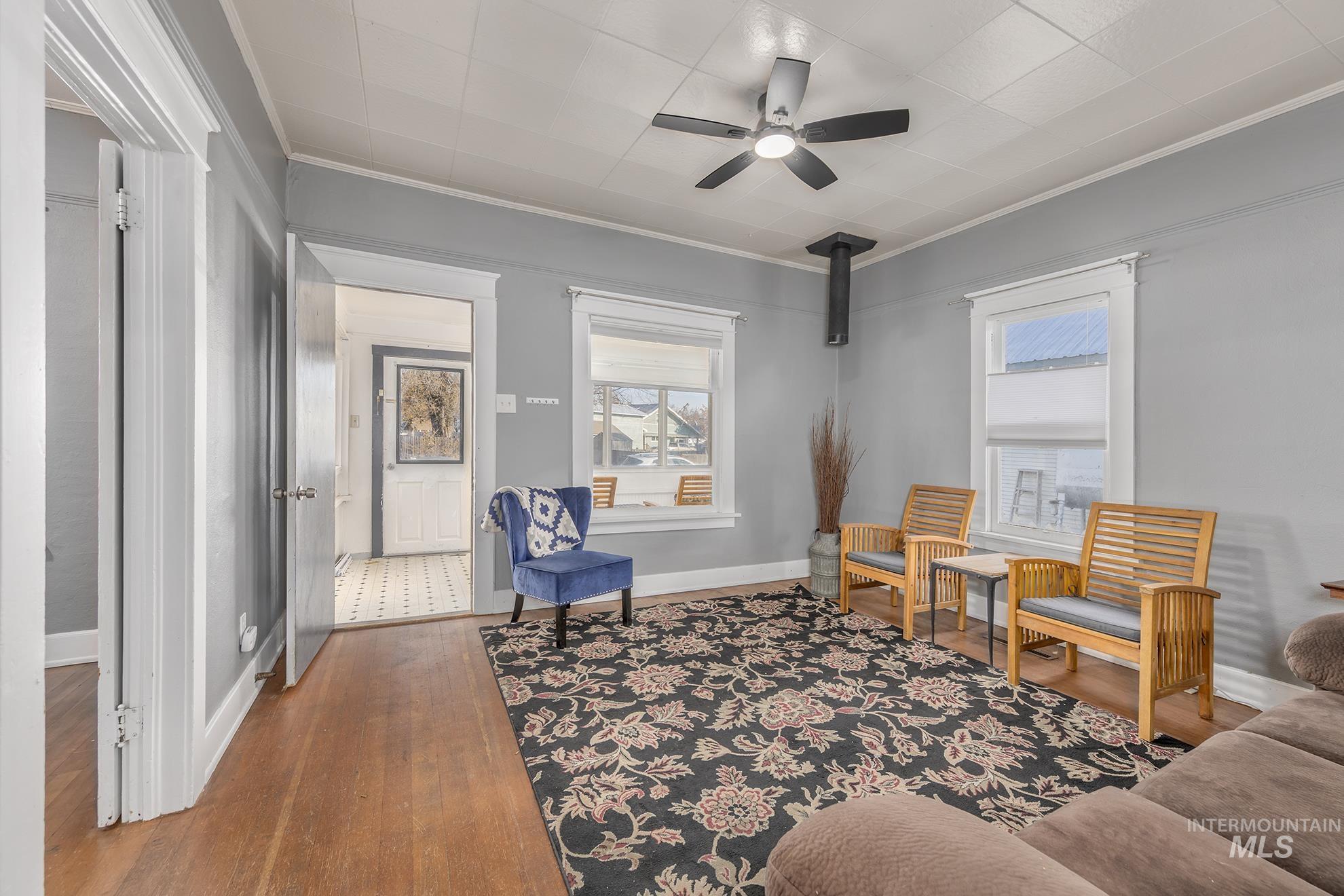 Living area featuring hardwood / wood-style floors, ceiling fan, and ornamental molding