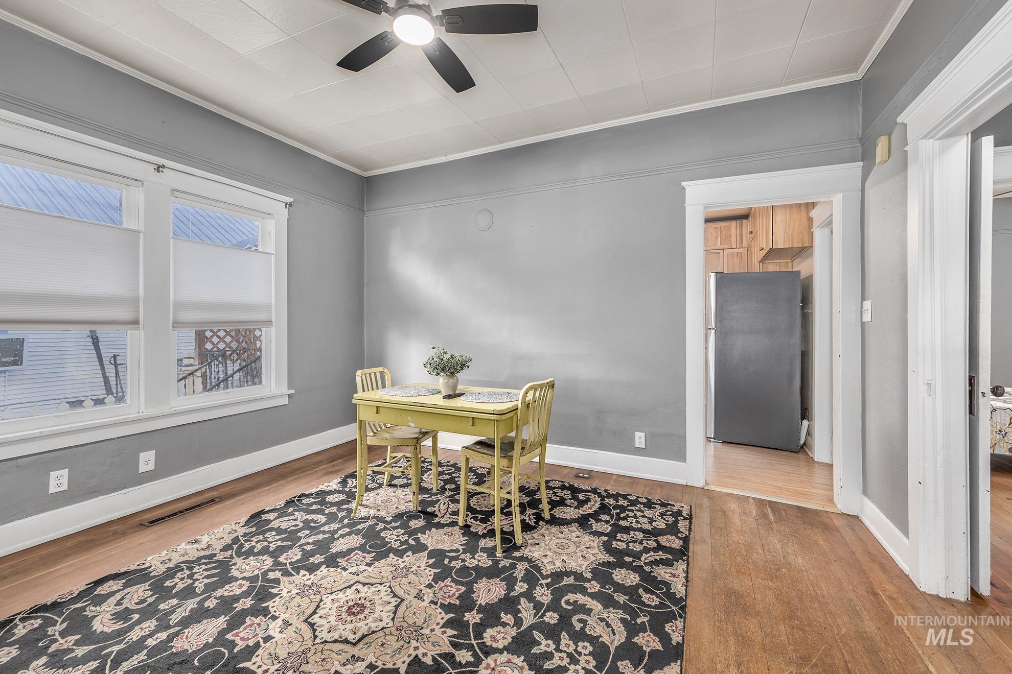 Dining space featuring wood finished floors, ornamental molding, an office area, and a ceiling fan