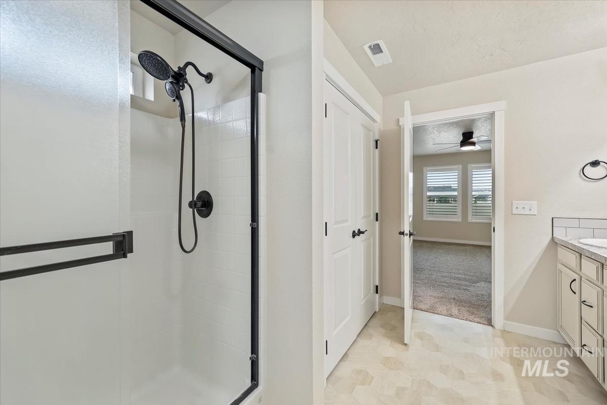 Bathroom featuring vanity, a shower stall, and a ceiling fan