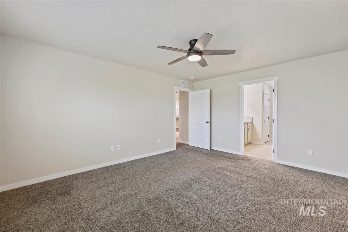 Unfurnished bedroom featuring carpet flooring, a ceiling fan, and ensuite bath