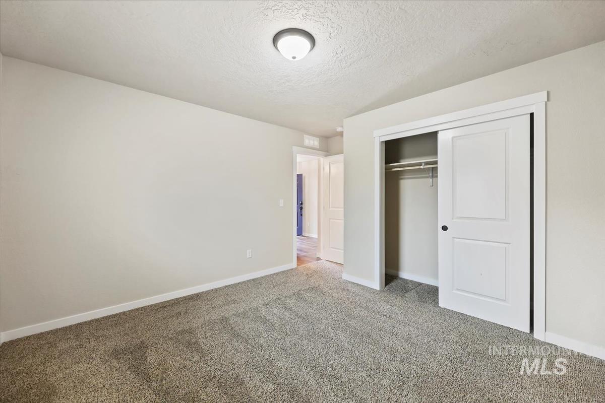Unfurnished bedroom with a textured ceiling, a closet, and carpet