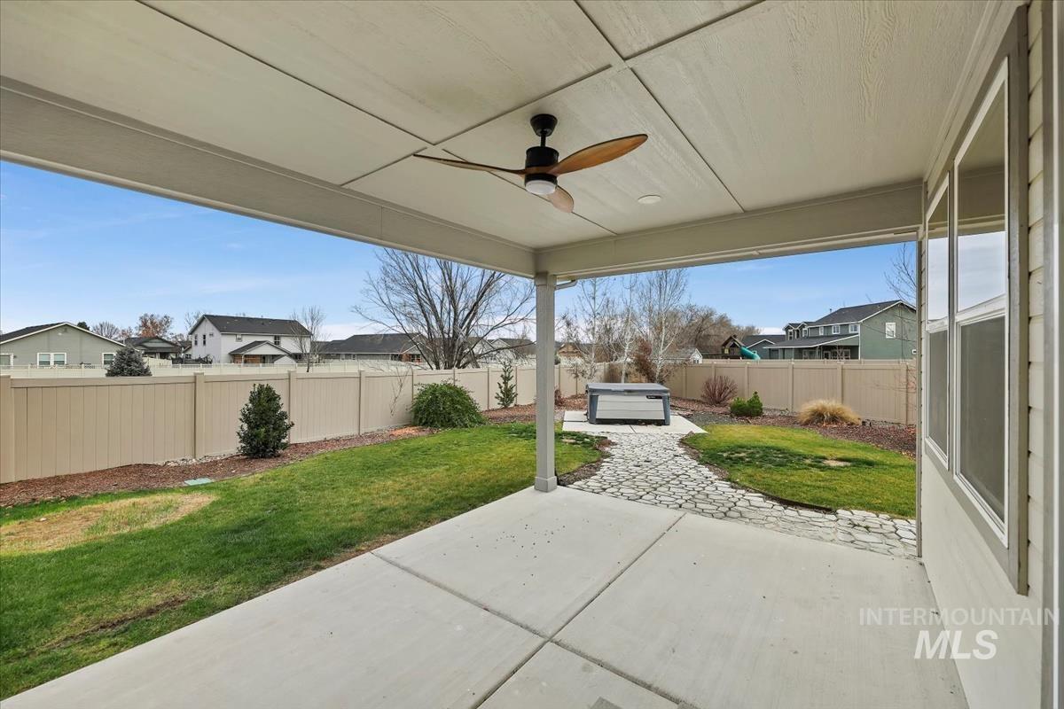 Fenced backyard featuring a patio area, ceiling fan, and a residential view