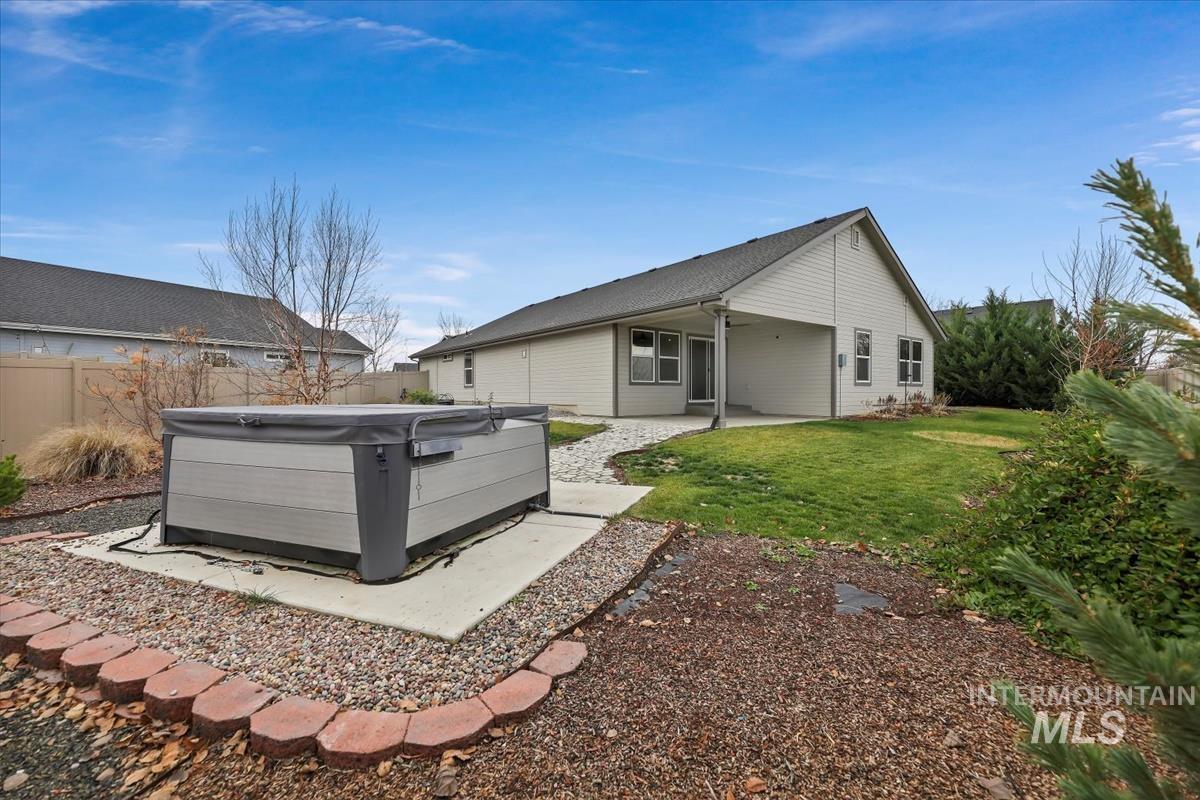 Rear view of property featuring a patio area, a fenced backyard, ceiling fan, and a hot tub