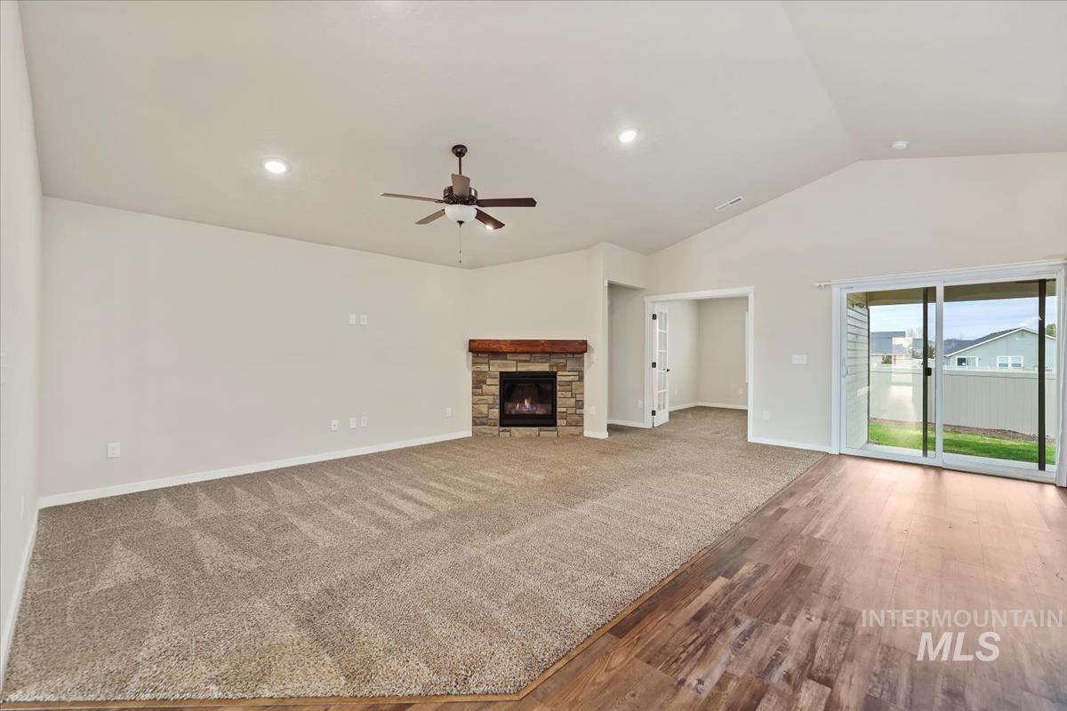 Unfurnished living room featuring lofted ceiling, ceiling fan, a fireplace, recessed lighting, and carpet