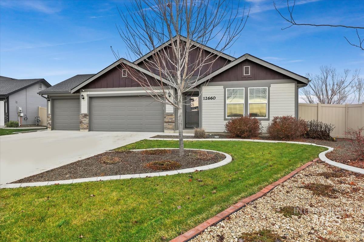 View of front of home featuring a garage, driveway, stone siding, and board and batten siding