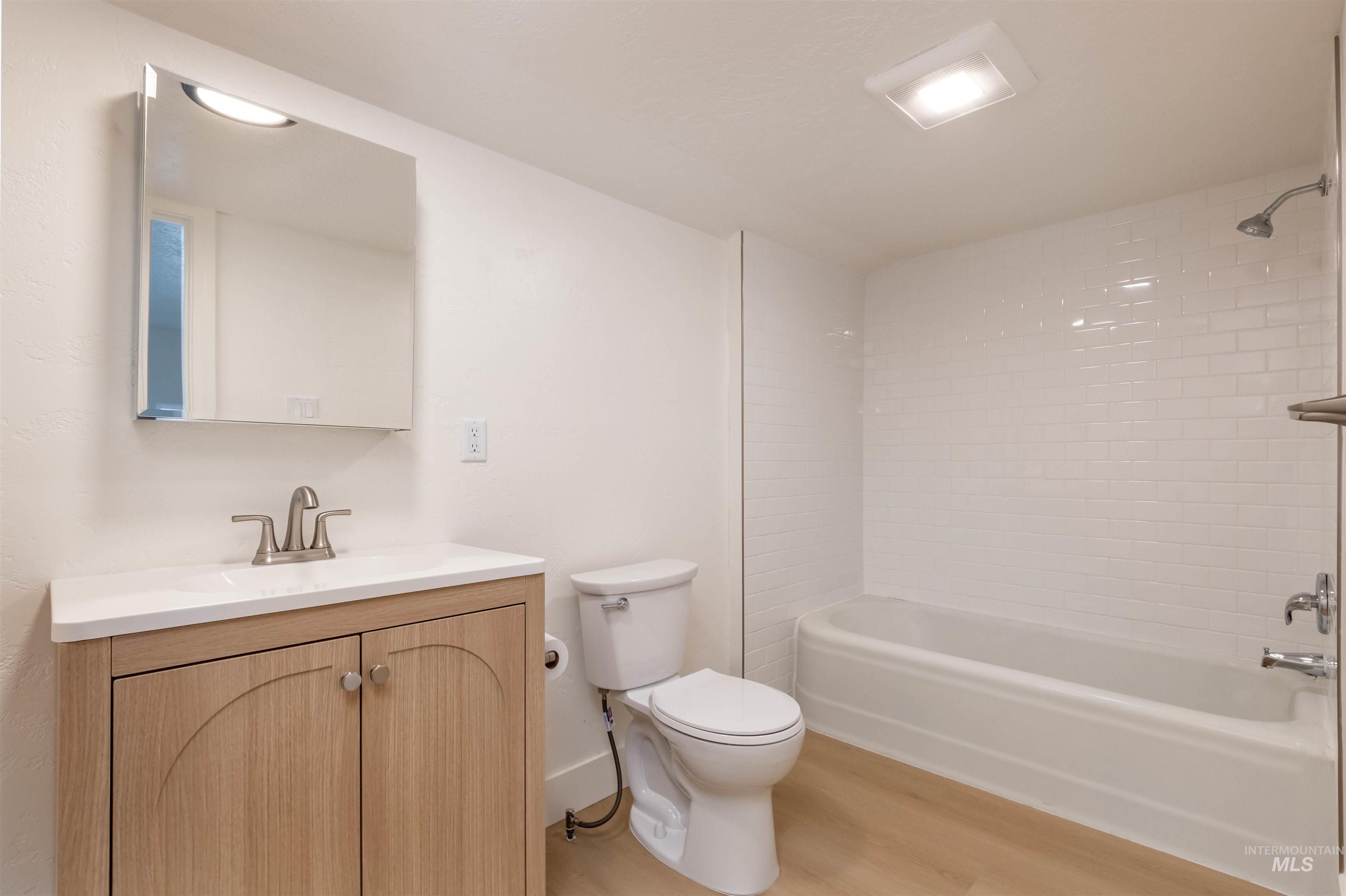 Full bathroom with shower / washtub combination, vanity, and light wood-type flooring