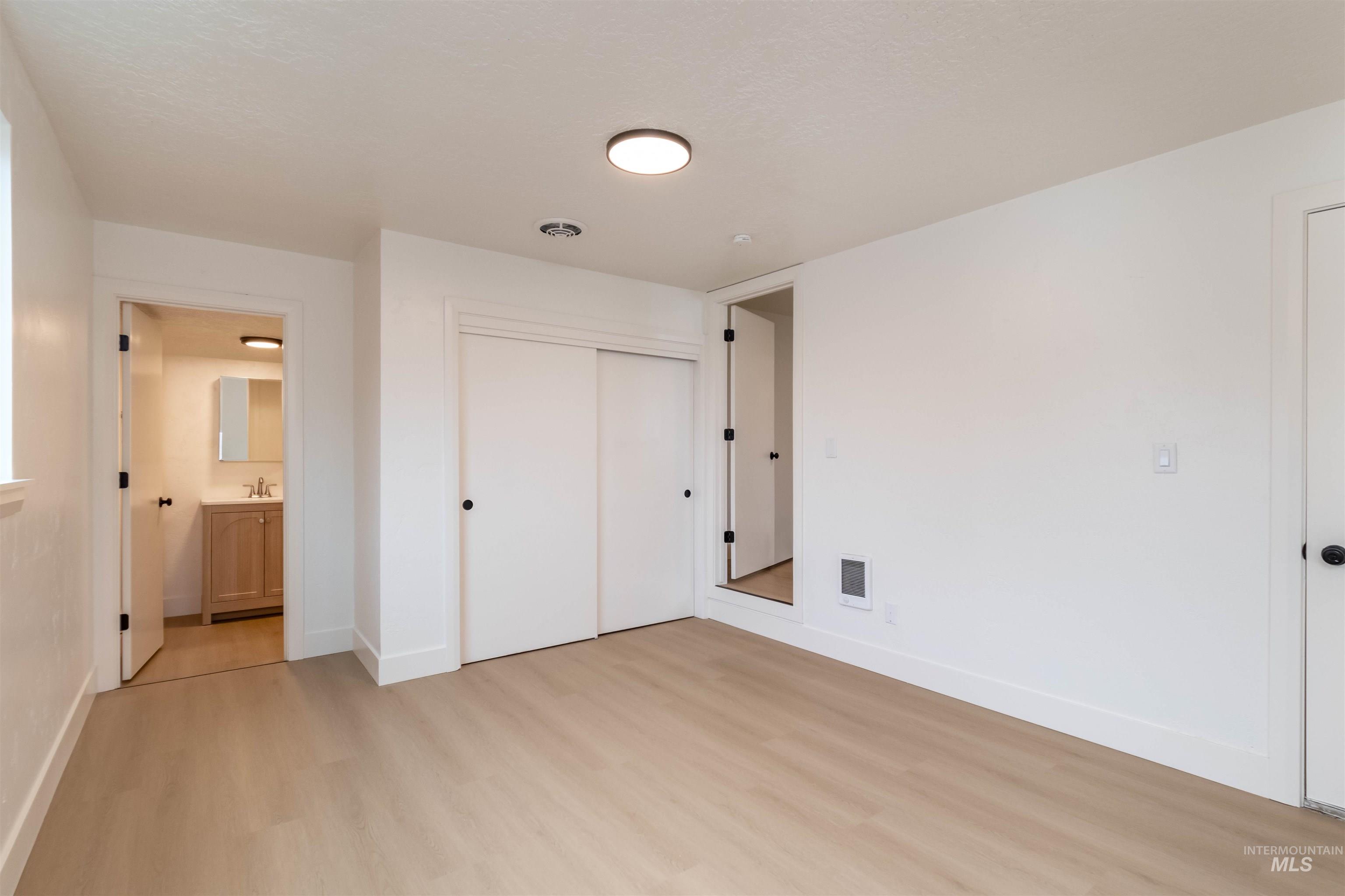 Unfurnished bedroom with light wood finished floors, a closet, and connected bathroom