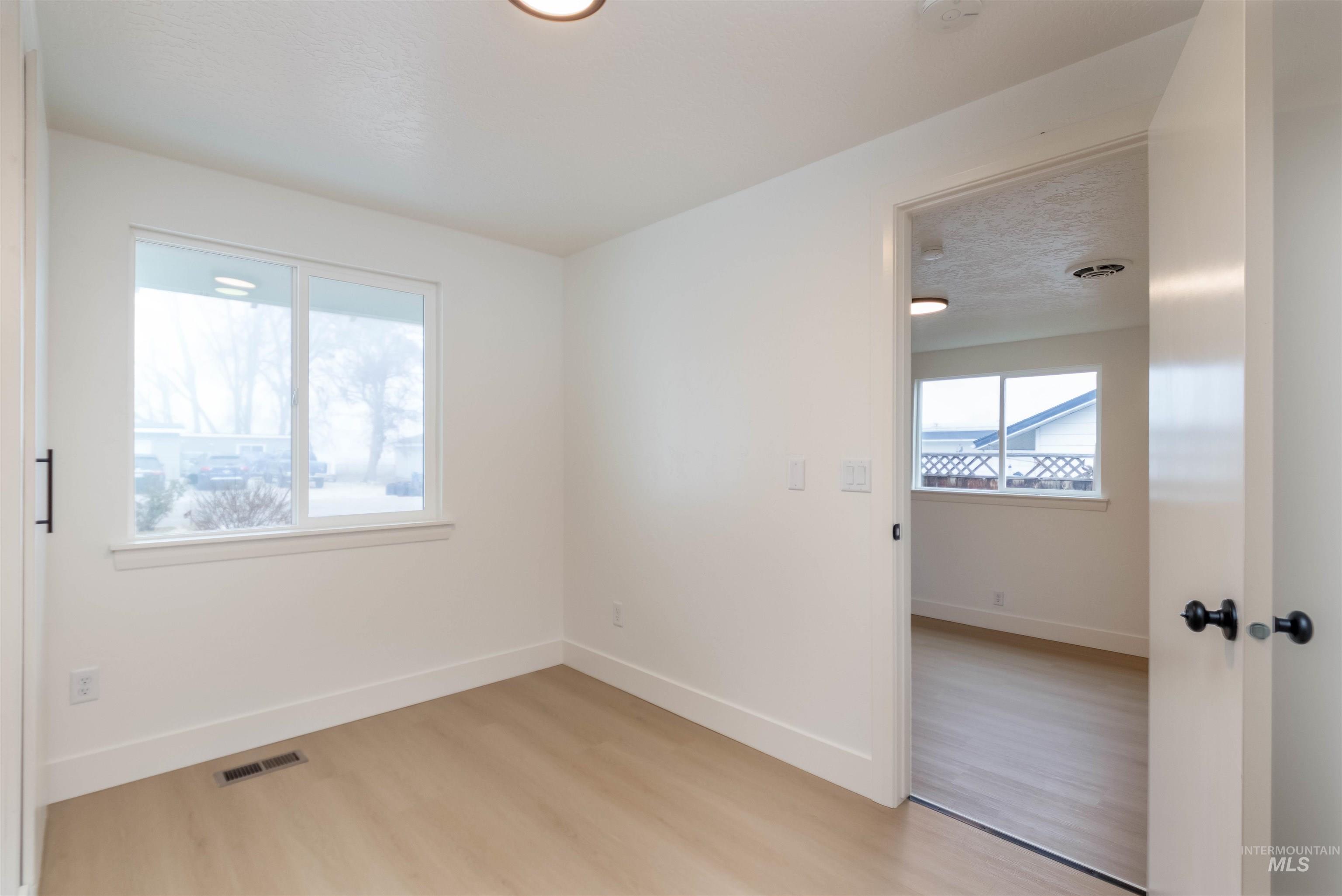 Empty room with light wood-type flooring and a textured ceiling