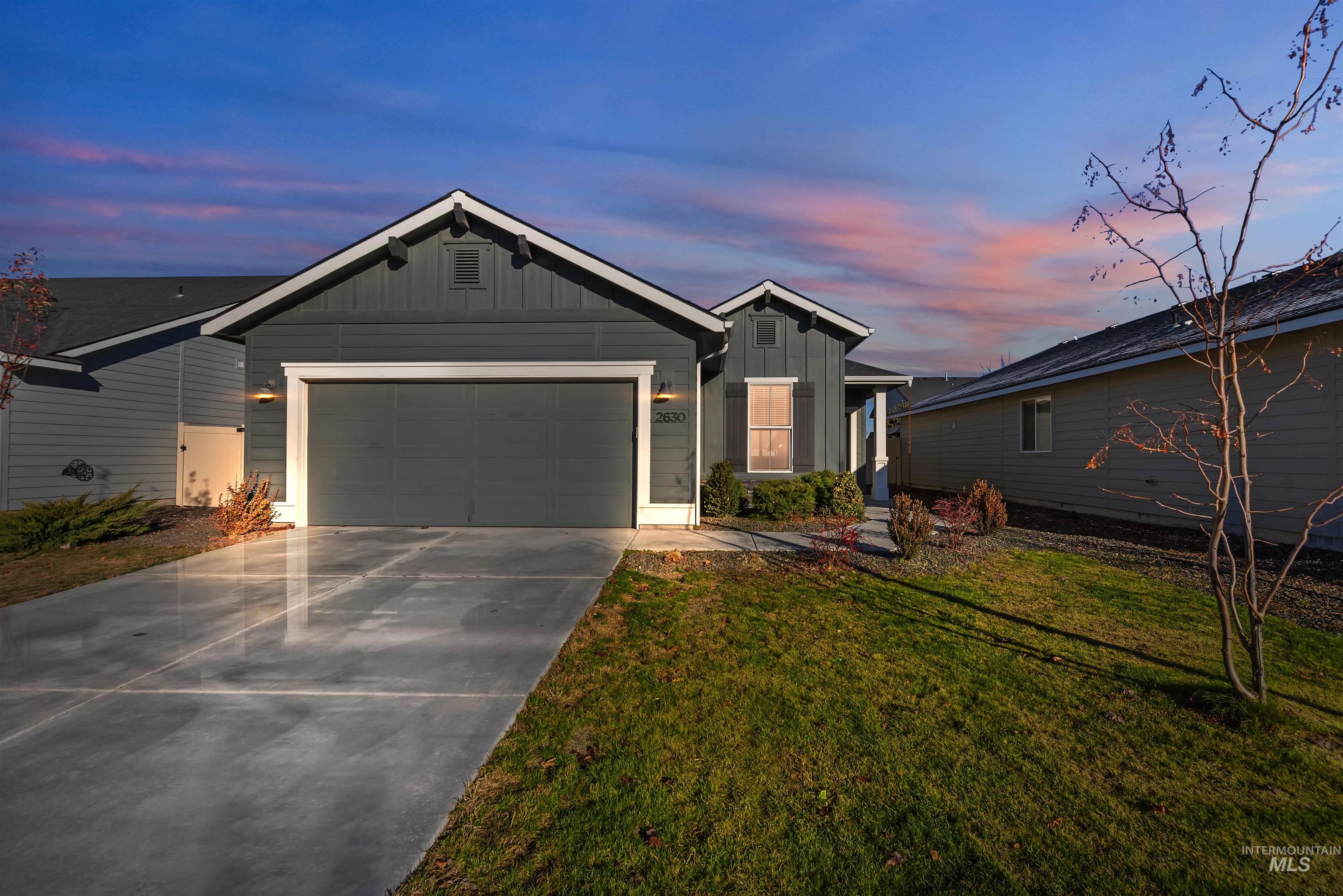 View of front of house featuring board and batten siding, driveway, an attached garage, and a front lawn
