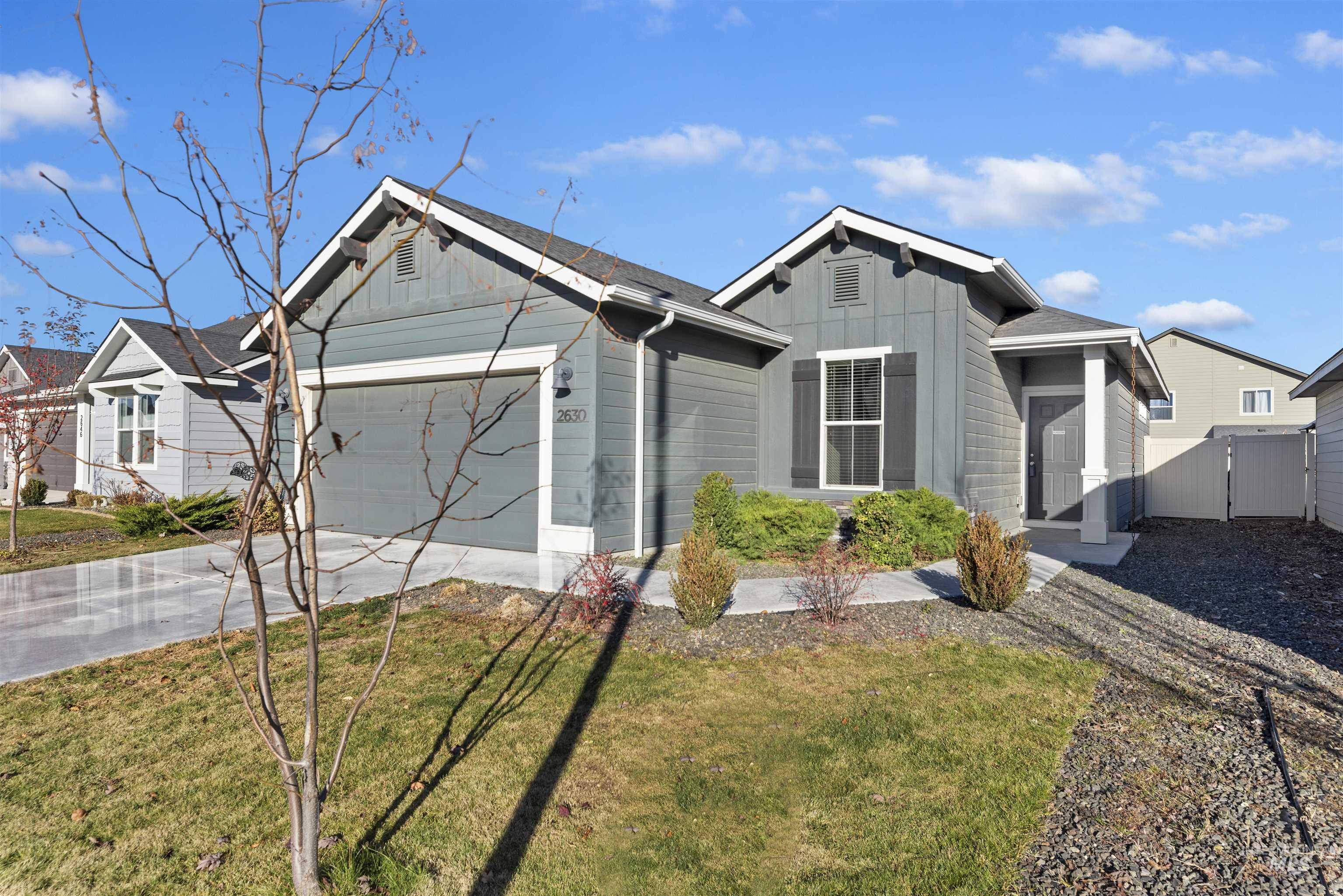 Ranch-style home with board and batten siding, driveway, a garage, and a front lawn