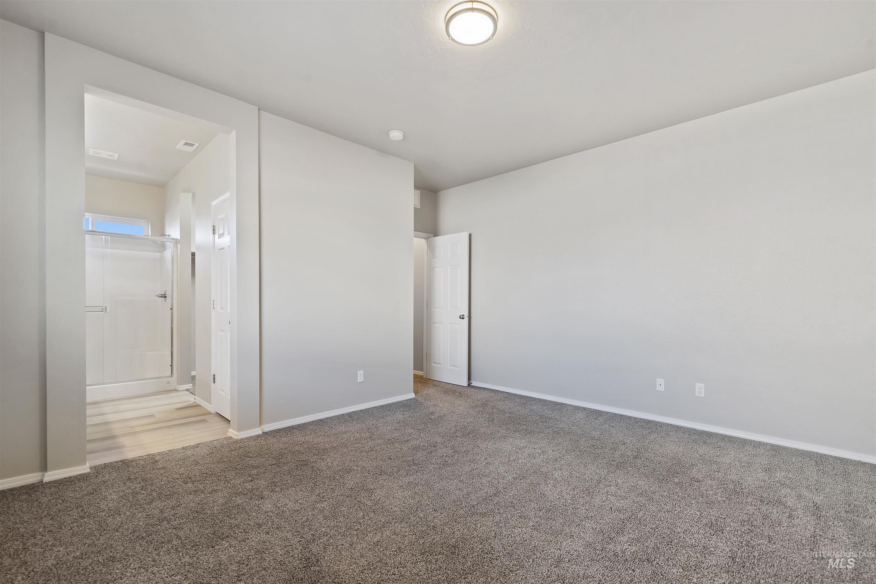 Unfurnished bedroom featuring light carpet and connected bathroom