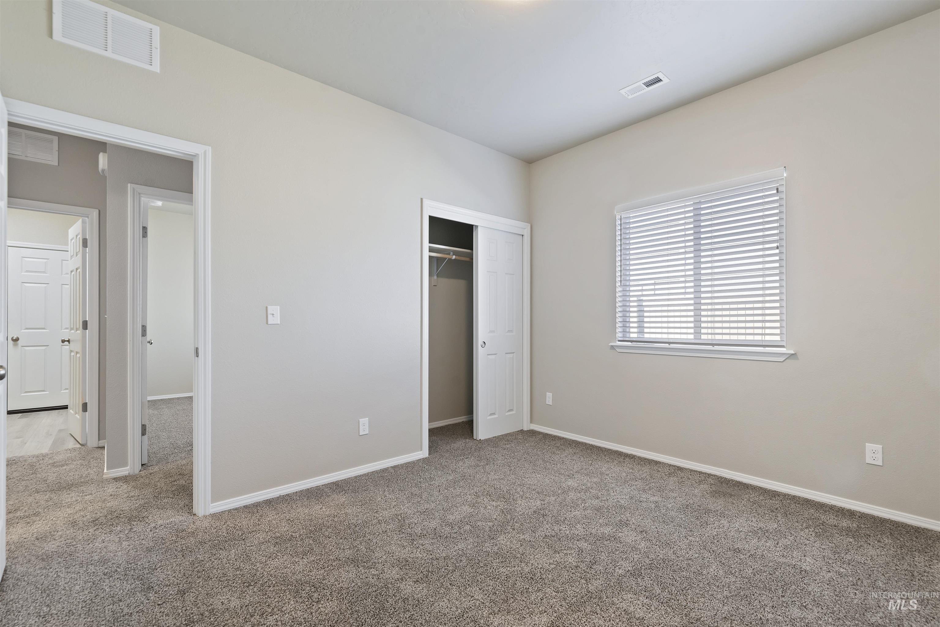 Unfurnished bedroom featuring light carpet and a closet