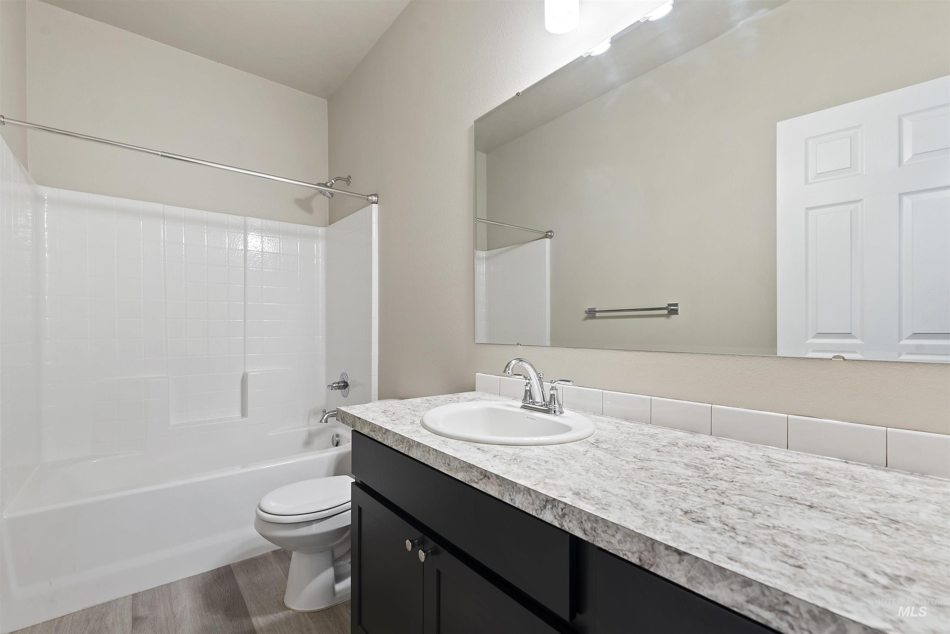 Bathroom with  shower combination, vanity, and dark wood-type flooring