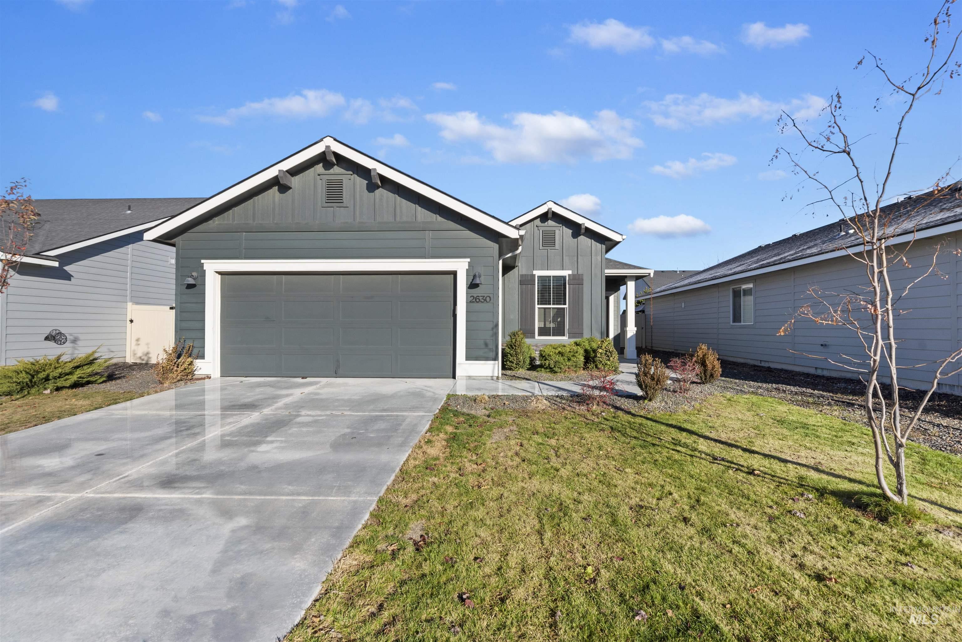 Single story home featuring board and batten siding, concrete driveway, a garage, and a front yard
