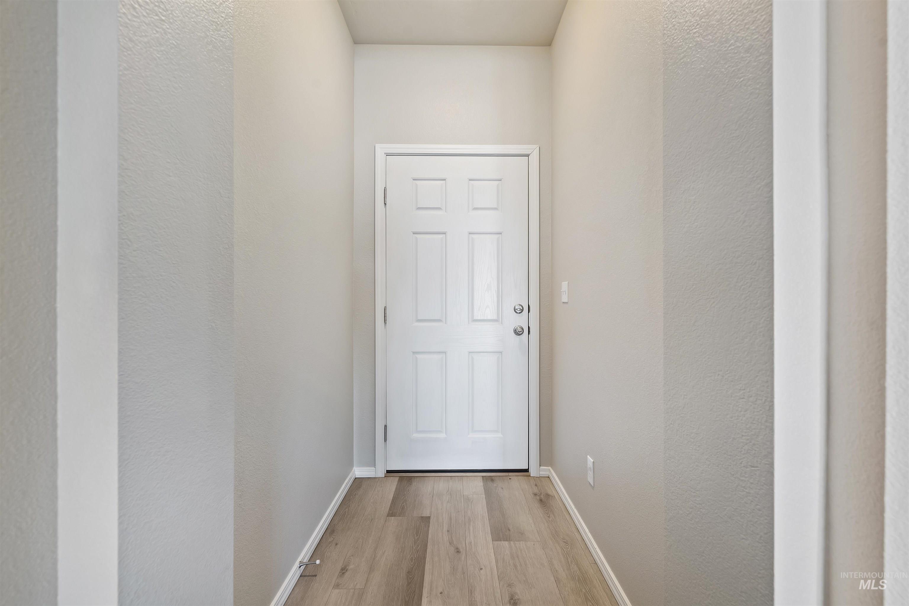 Doorway featuring a textured wall and wood finished floors