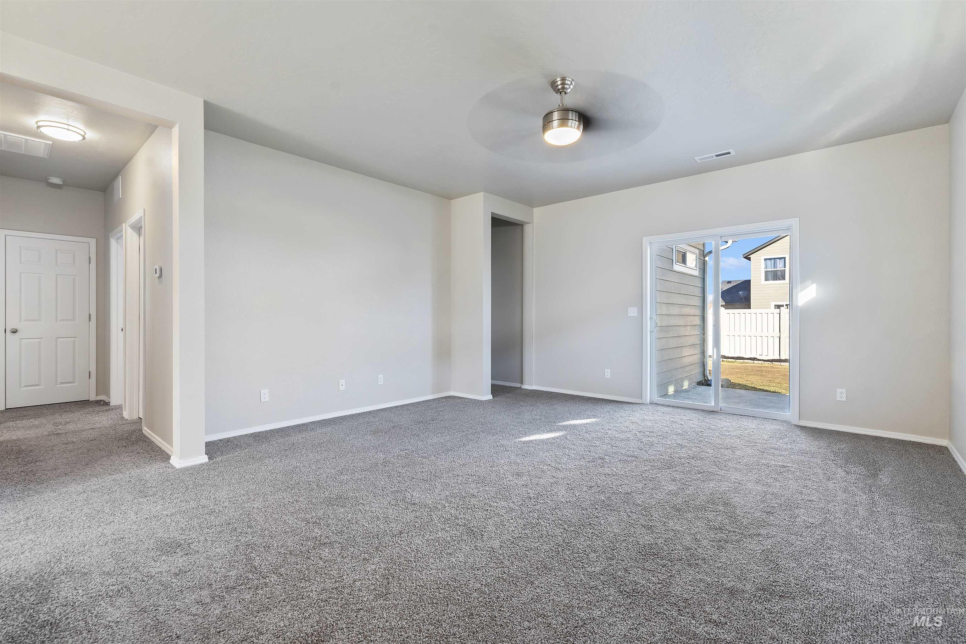 Carpeted empty room featuring a ceiling fan and baseboards