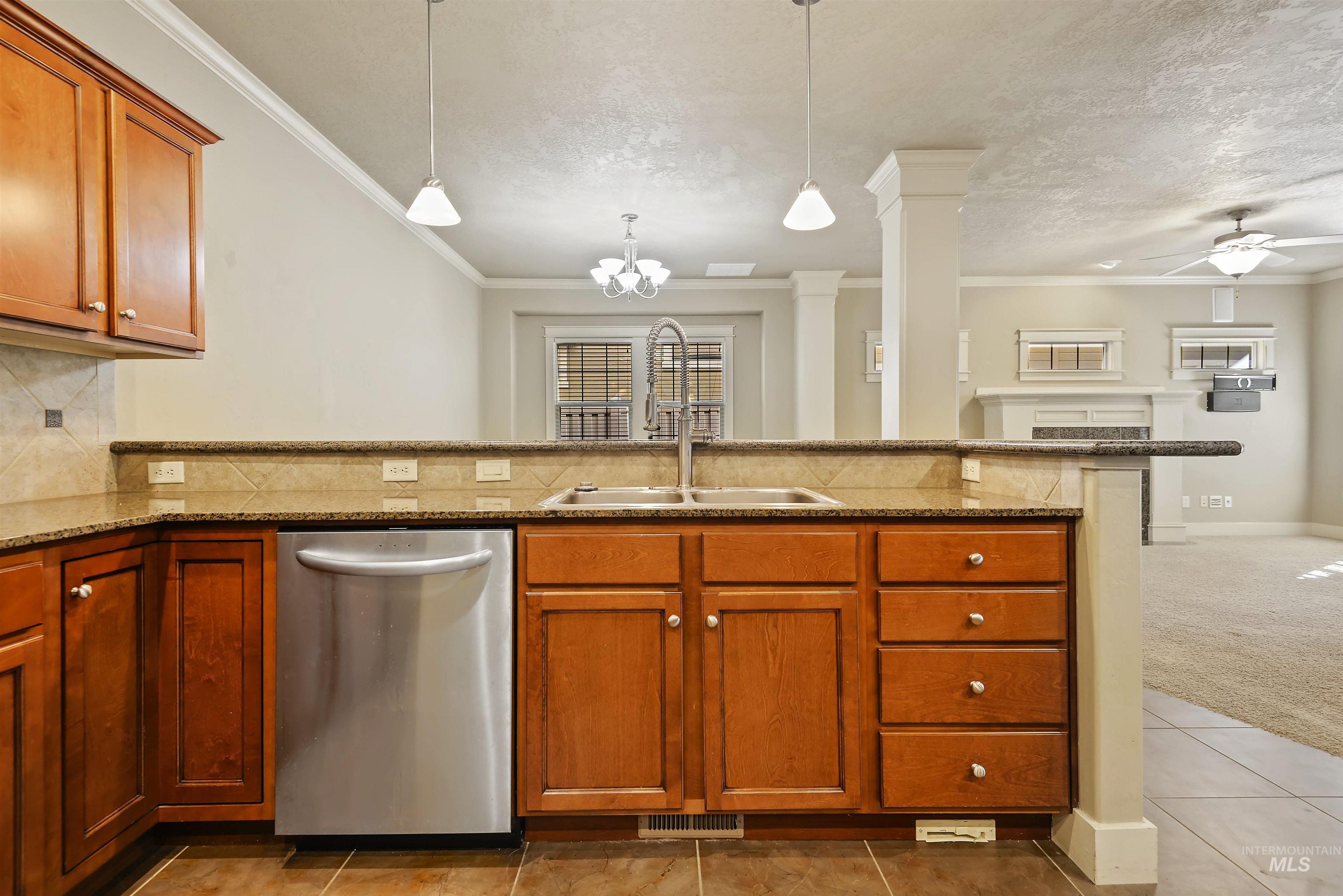 Kitchen featuring dishwasher, brown cabinets, decorative backsplash, crown molding, and a textured ceiling