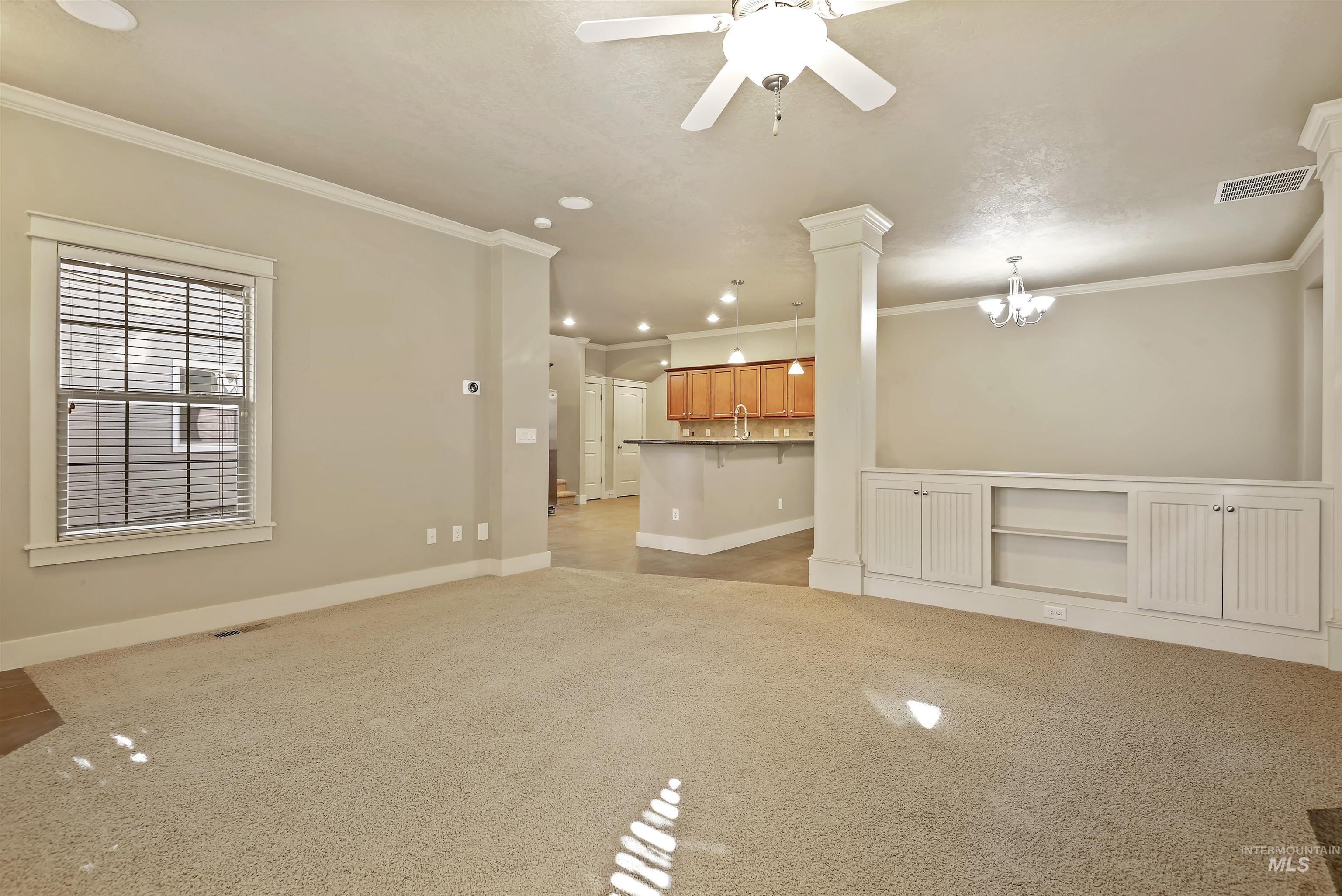 Unfurnished living room with light carpet, ornamental molding, a ceiling fan, recessed lighting, and ornate columns