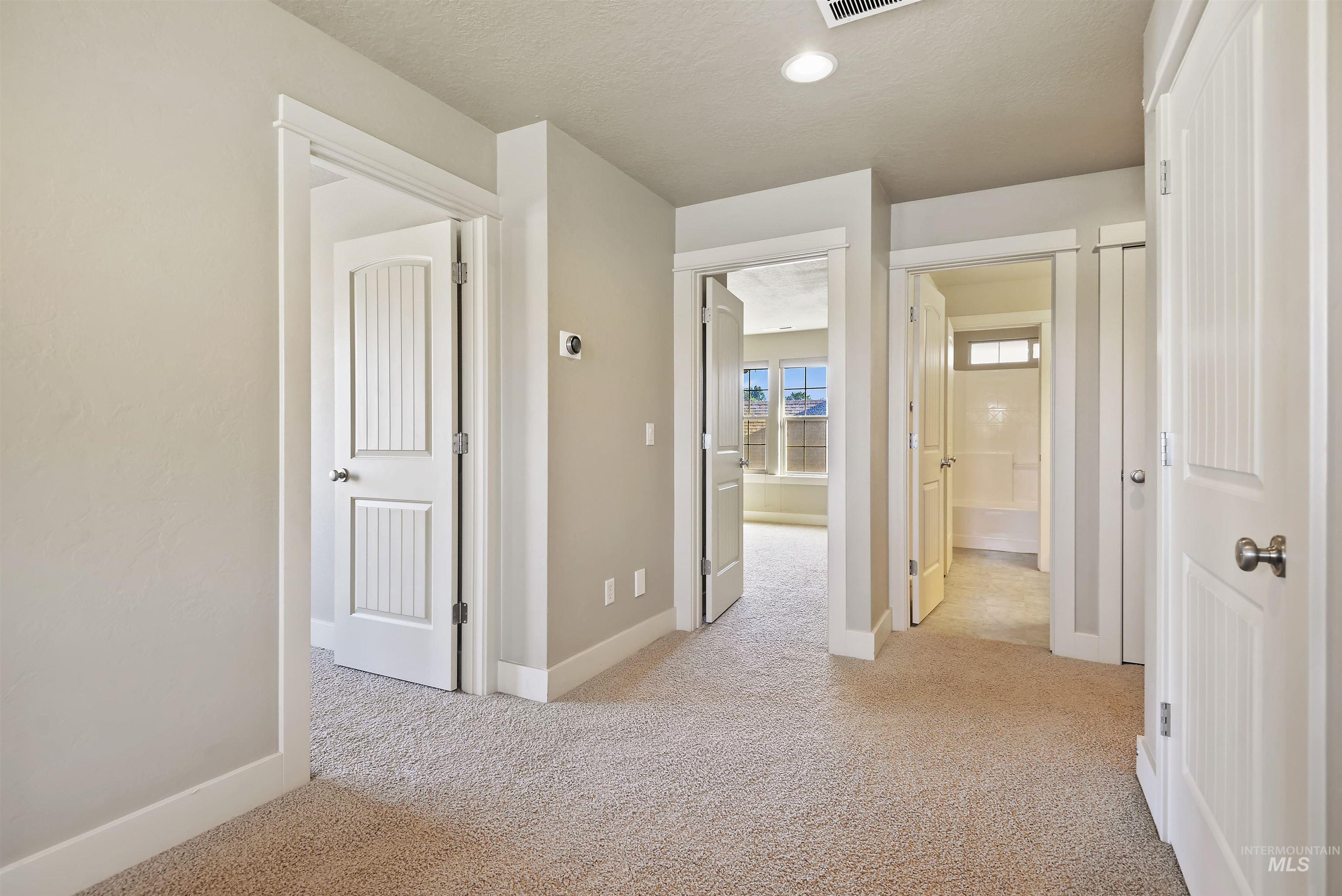 Hall featuring light colored carpet, a textured ceiling, and recessed lighting