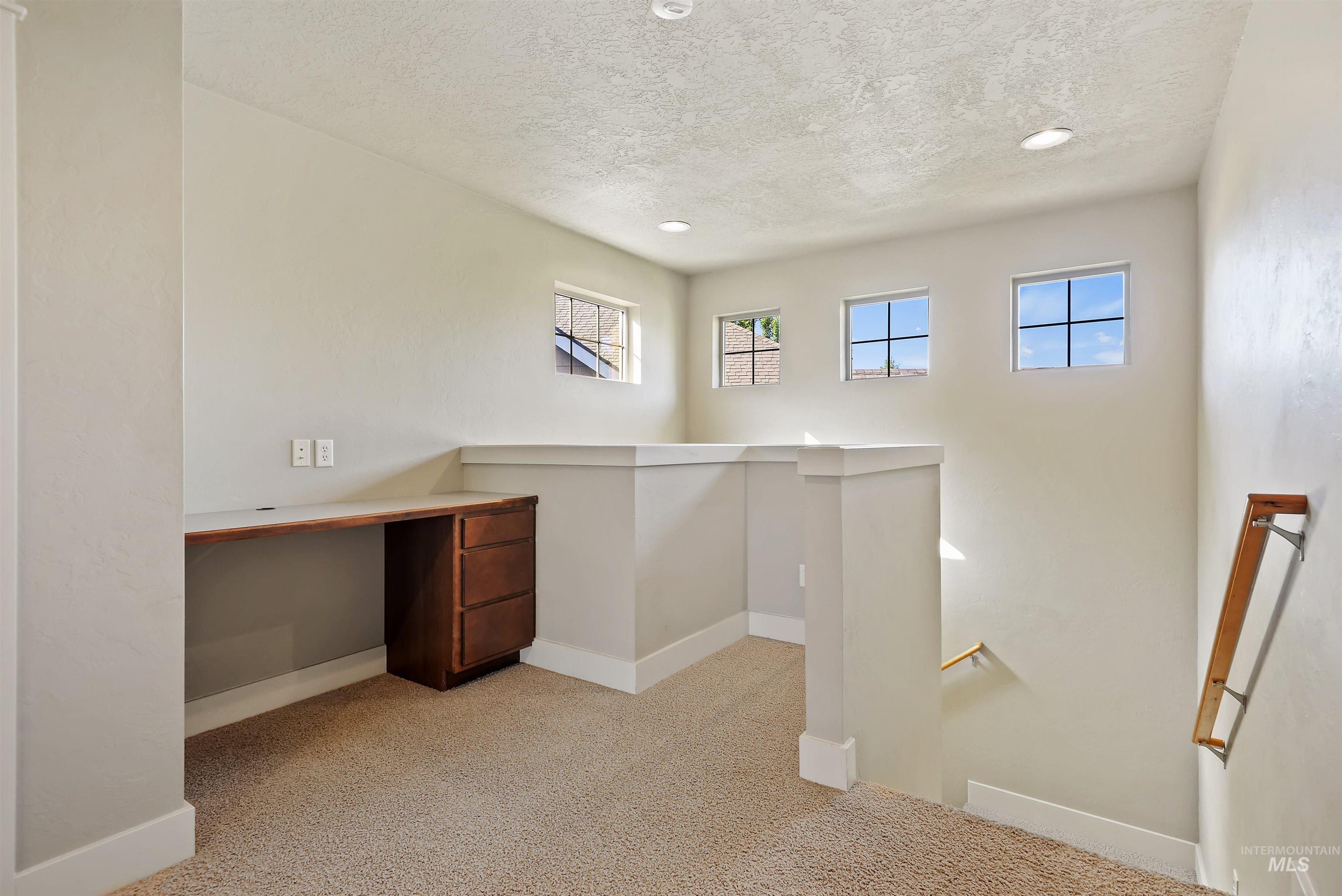 Unfurnished office with light colored carpet, built in study area, a textured ceiling, and recessed lighting