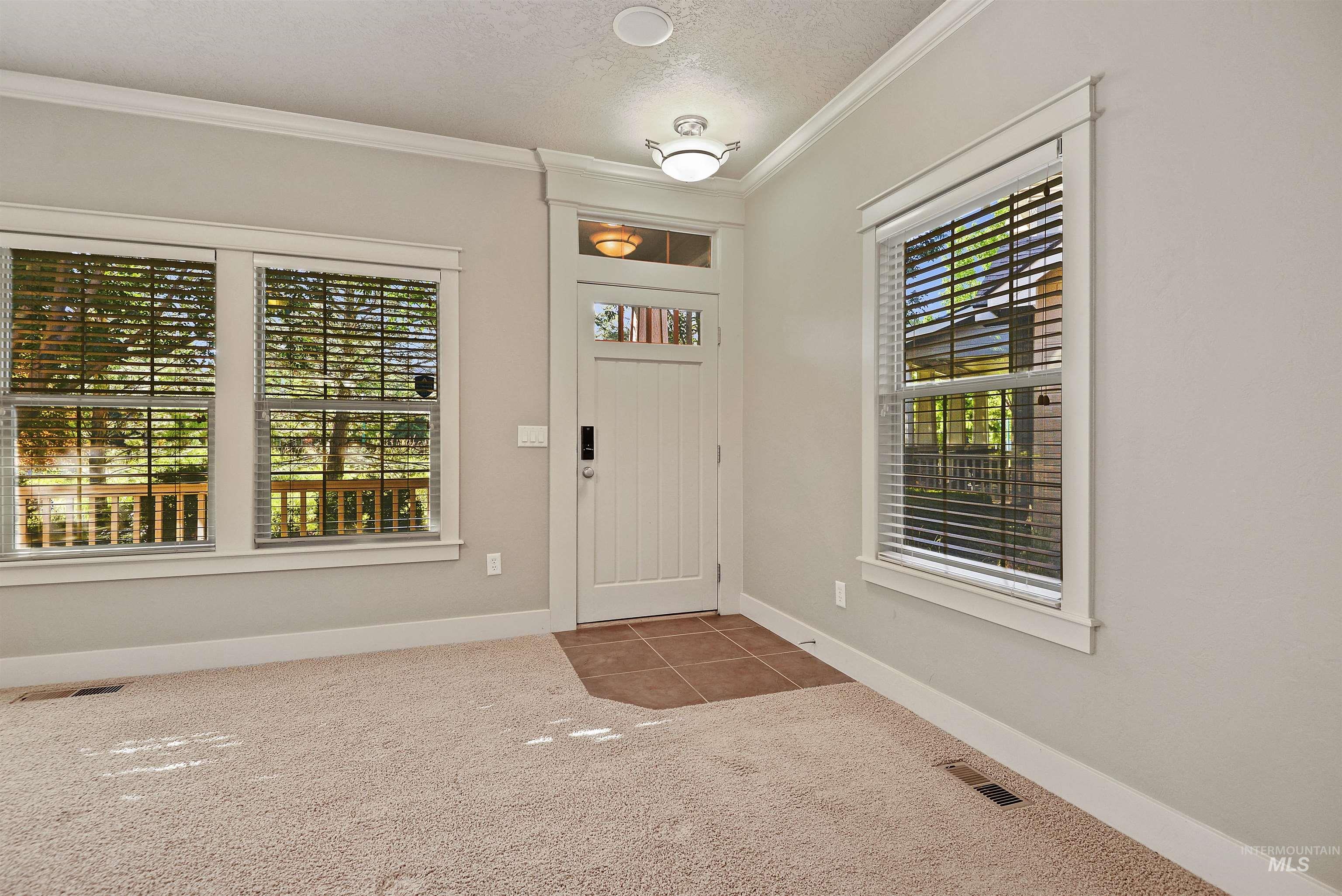 Foyer featuring ornamental molding, a textured ceiling, dark carpet, and dark tile patterned floors