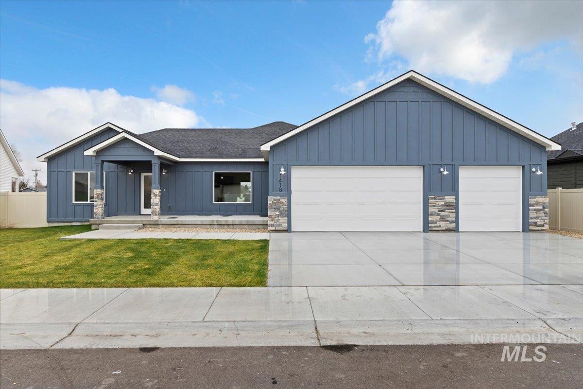 View of front of home featuring board and batten siding, stone siding, driveway, and a garage