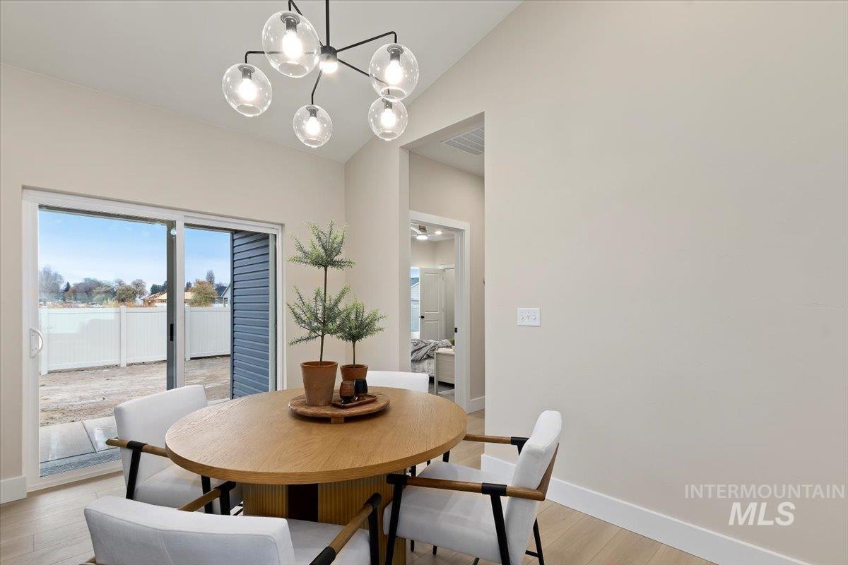 Dining area with light wood finished floors, vaulted ceiling, and a chandelier