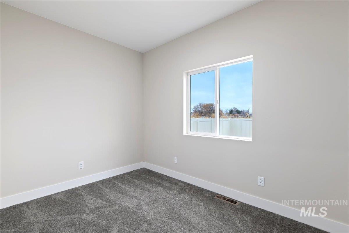 Empty room with baseboards and dark carpet