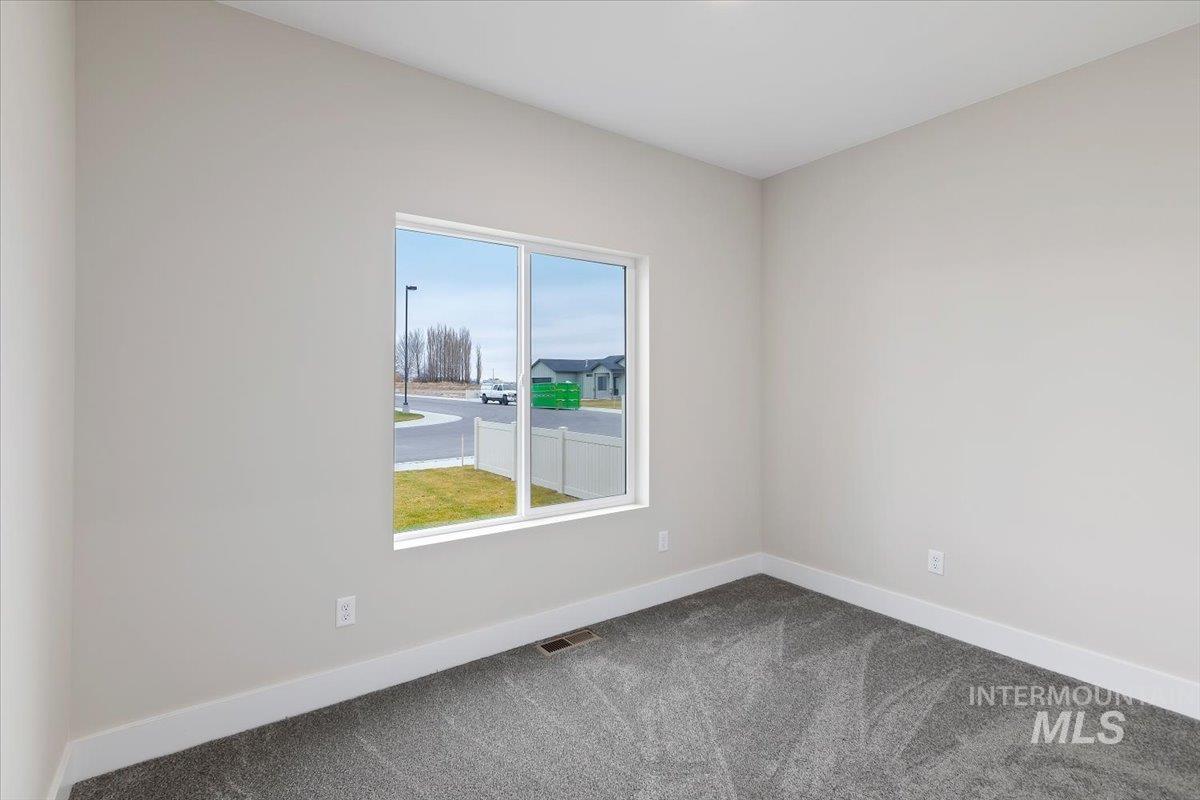 Carpeted spare room featuring baseboards