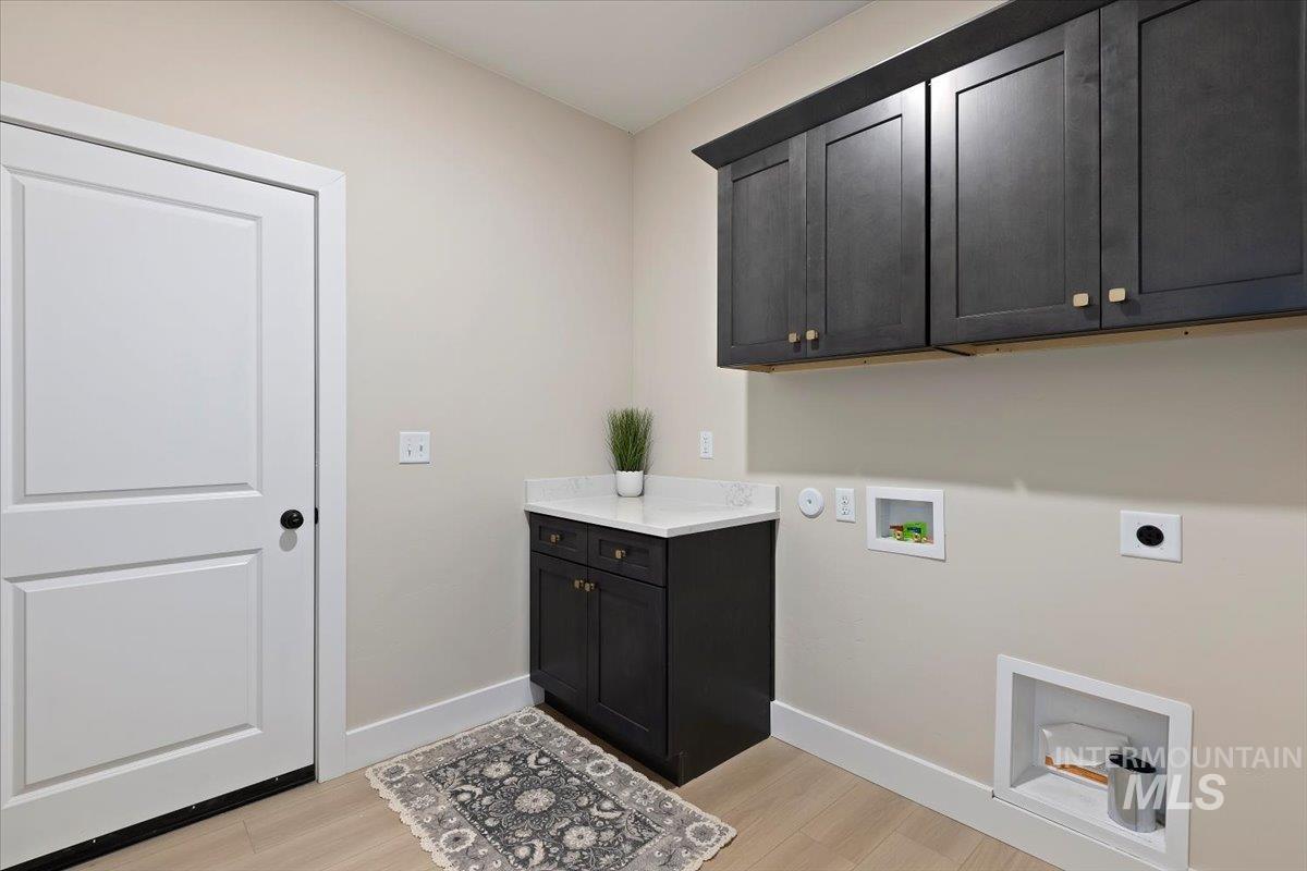 Washroom featuring washer hookup, electric dryer hookup, light wood-style floors, and cabinet space