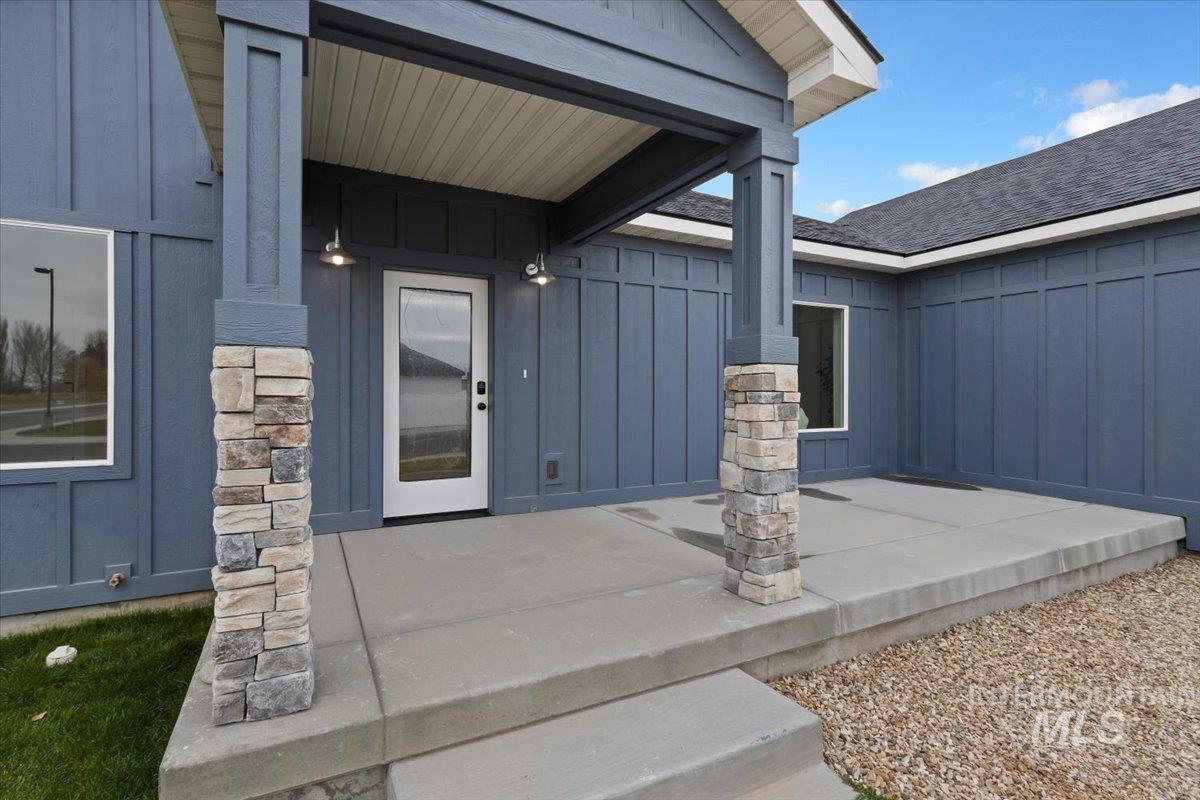 View of exterior entry featuring board and batten siding, a porch, and stone siding