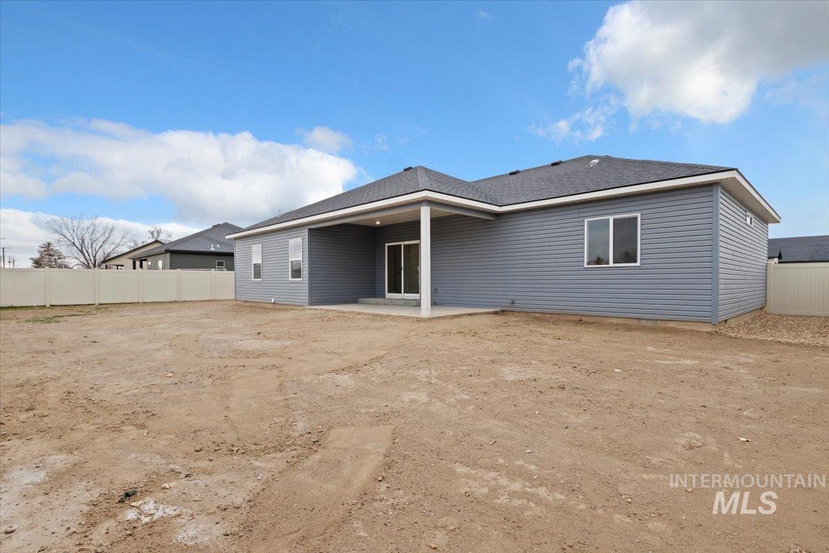 Rear view of house featuring a patio and a shingled roof