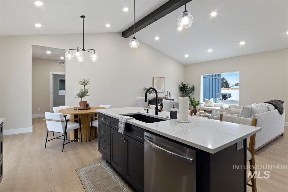 Kitchen with decorative light fixtures, stainless steel dishwasher, open floor plan, dark cabinetry, and light stone countertops
