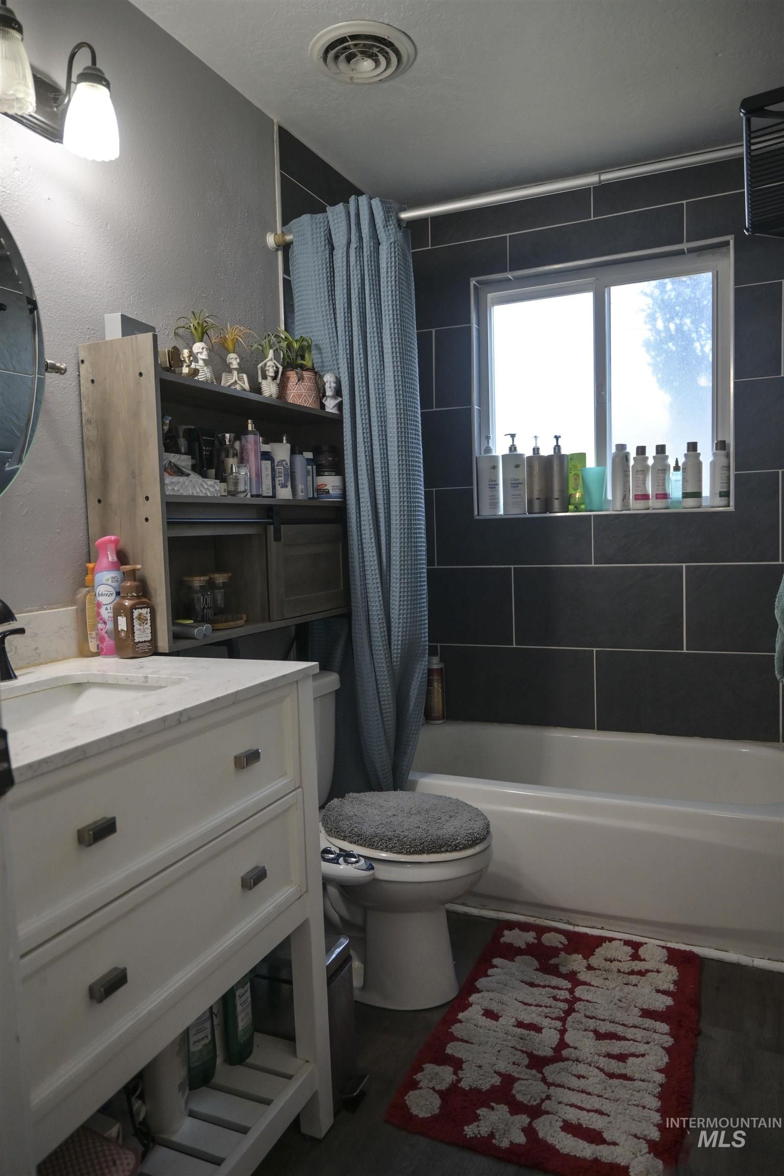 Bathroom with shower / bath combo, vanity, a textured wall, and a textured ceiling