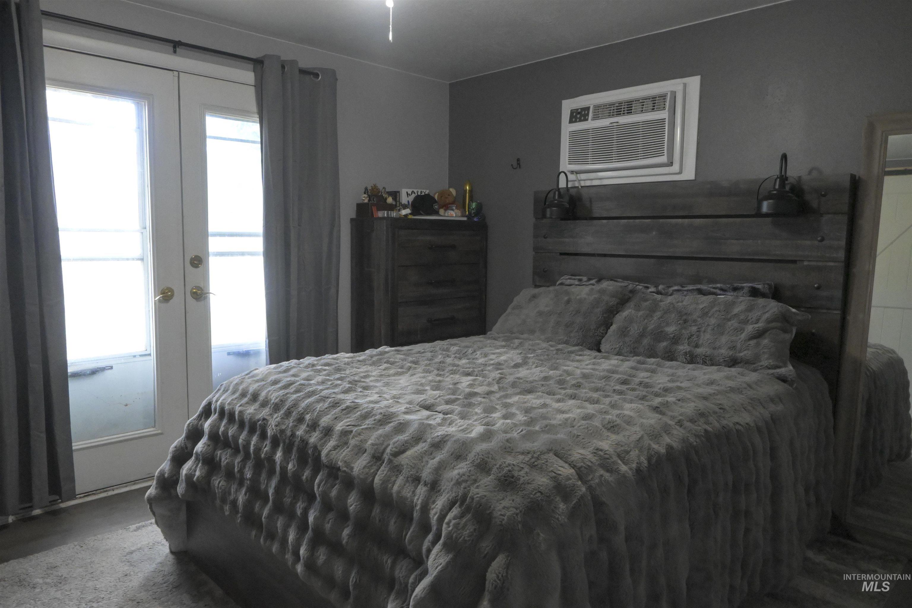 Bedroom featuring french doors, access to exterior, and an AC wall unit
