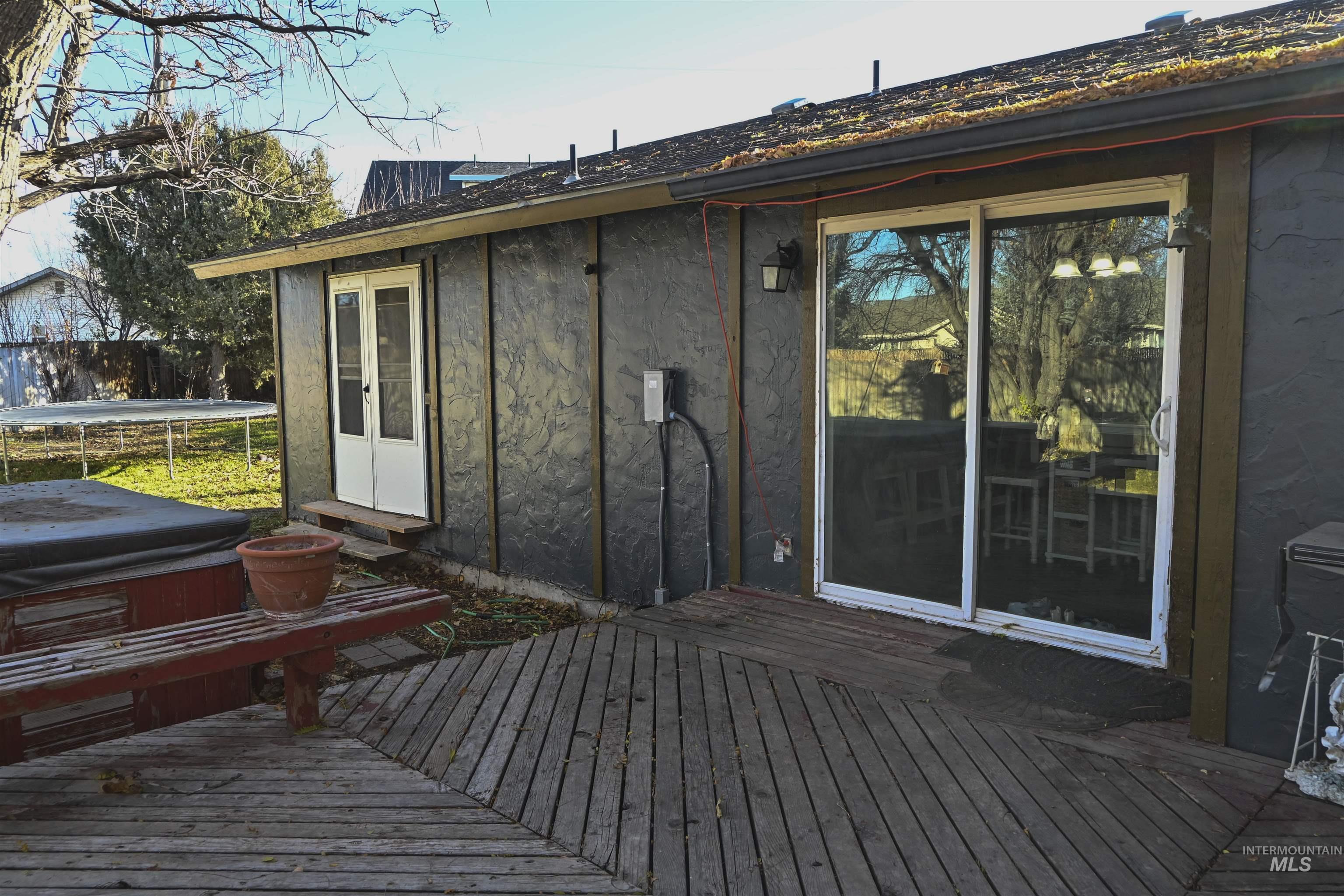 Wooden terrace featuring a trampoline and a hot tub