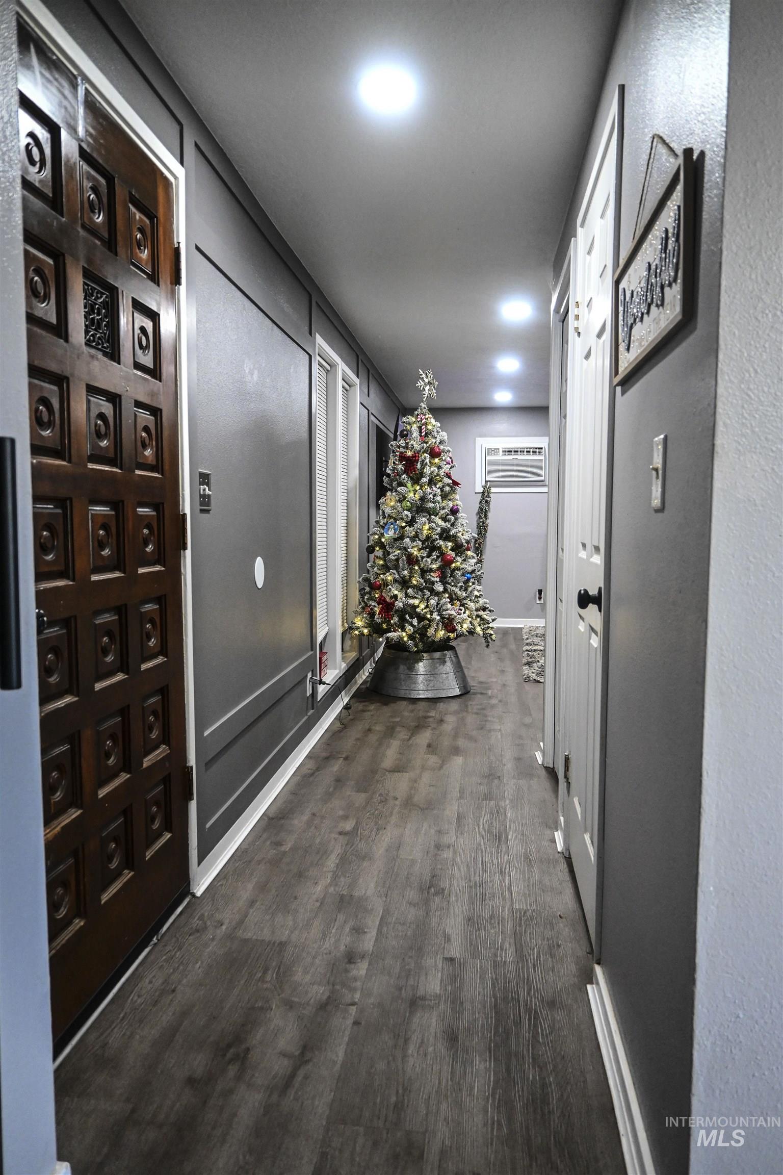 Hall featuring dark wood-type flooring, recessed lighting, and a textured wall