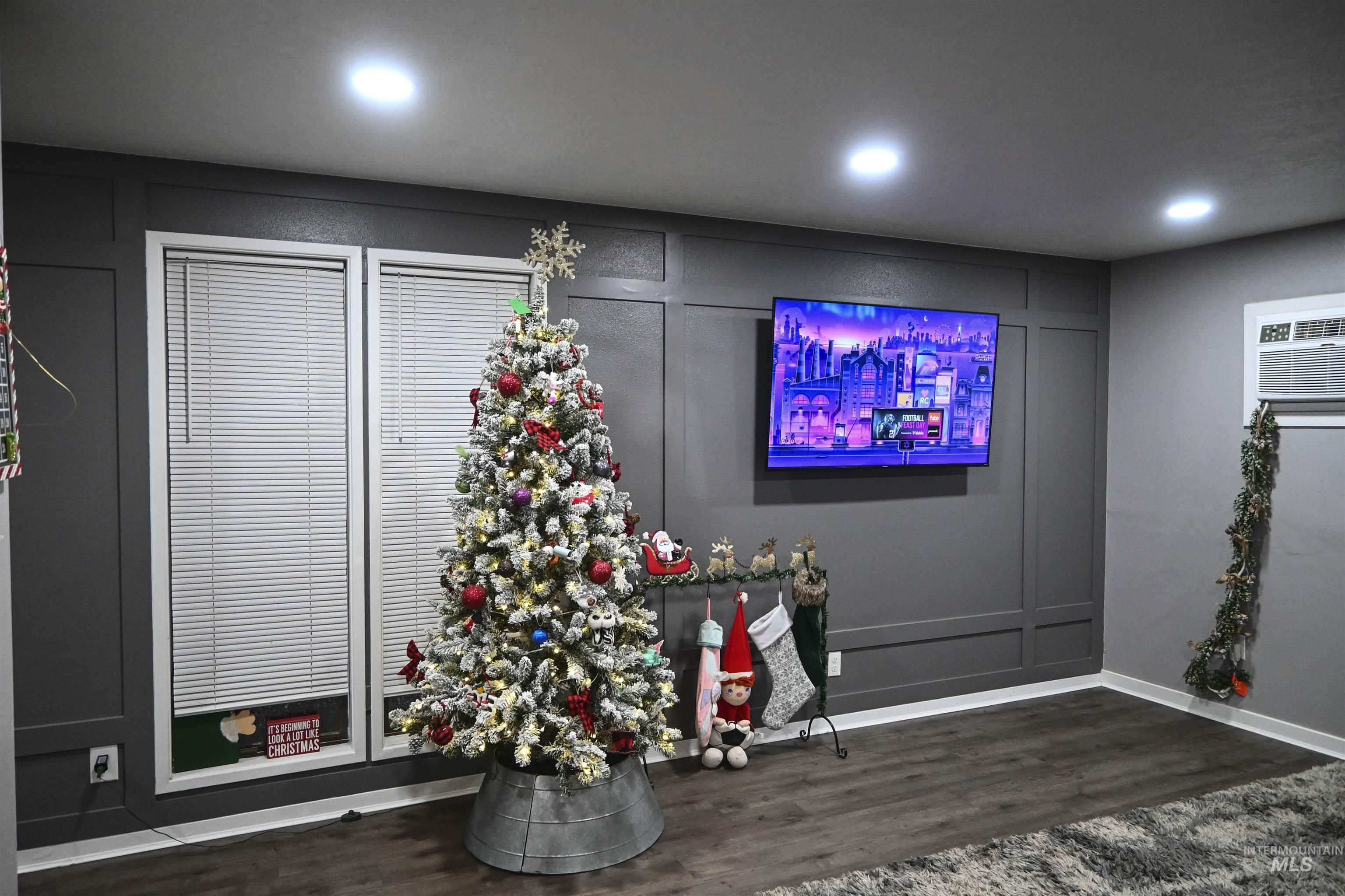 Detailed view of wood finished floors, a decorative wall, a wall mounted air conditioner, and recessed lighting
