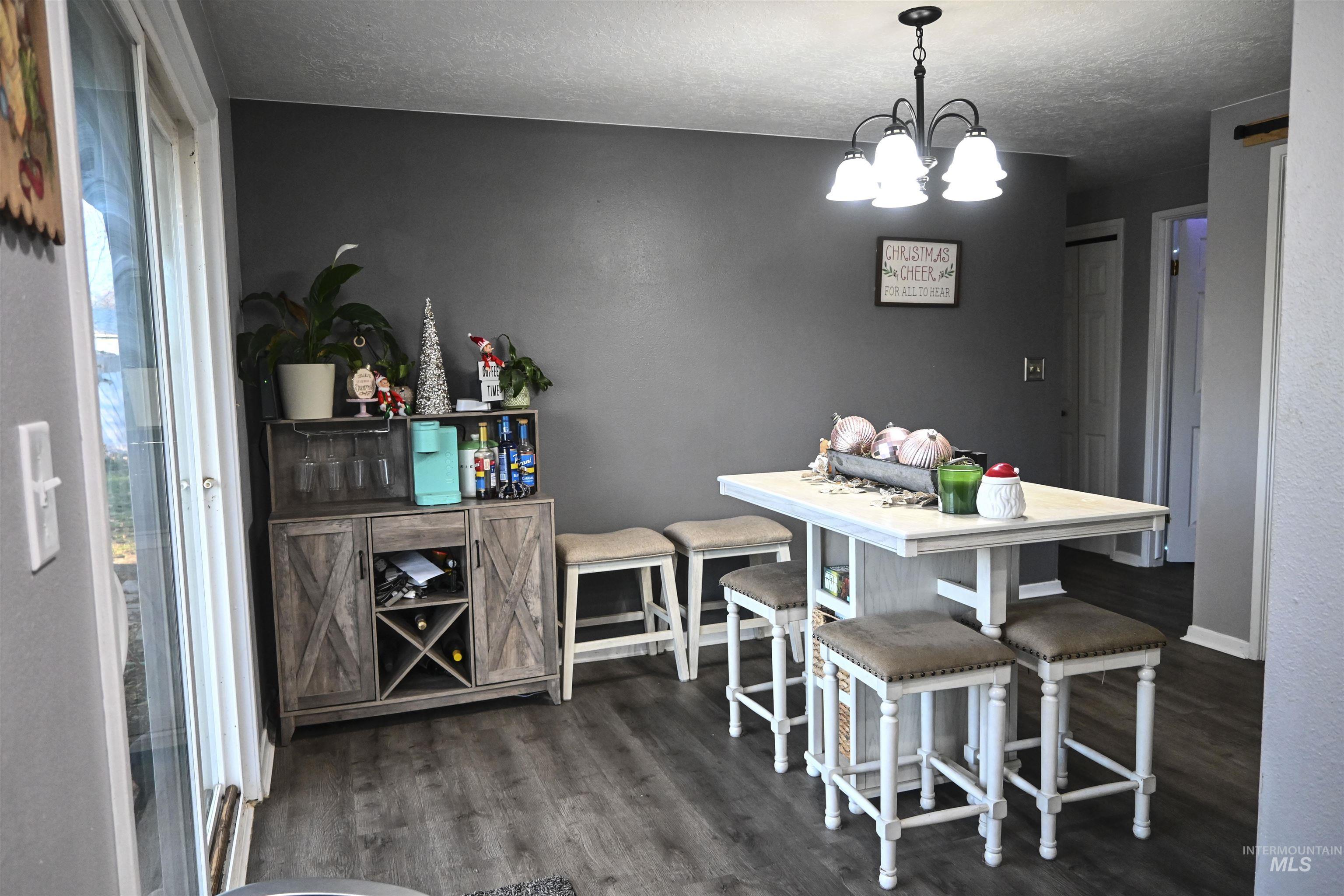 Dining area featuring dark wood-style flooring, a textured ceiling, and a chandelier