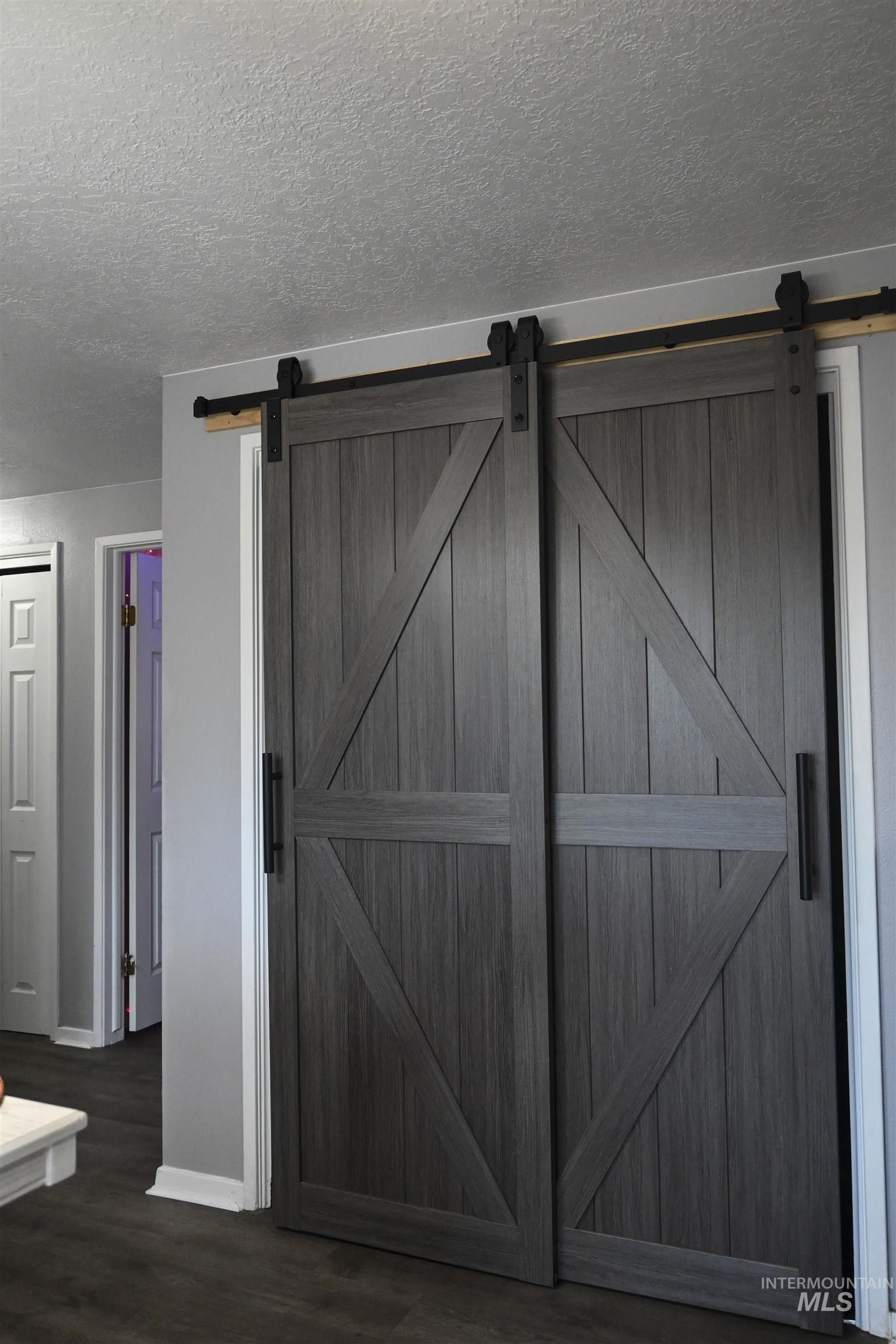 Detailed view of a textured ceiling, wood finished floors, and a barn door