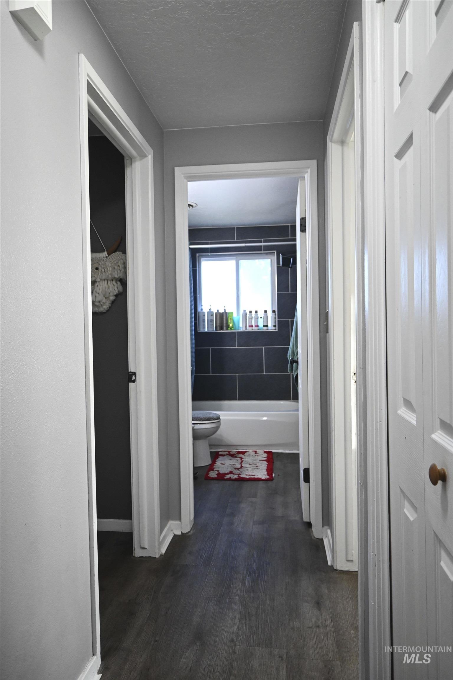 Hallway featuring dark wood-style floors and a textured ceiling