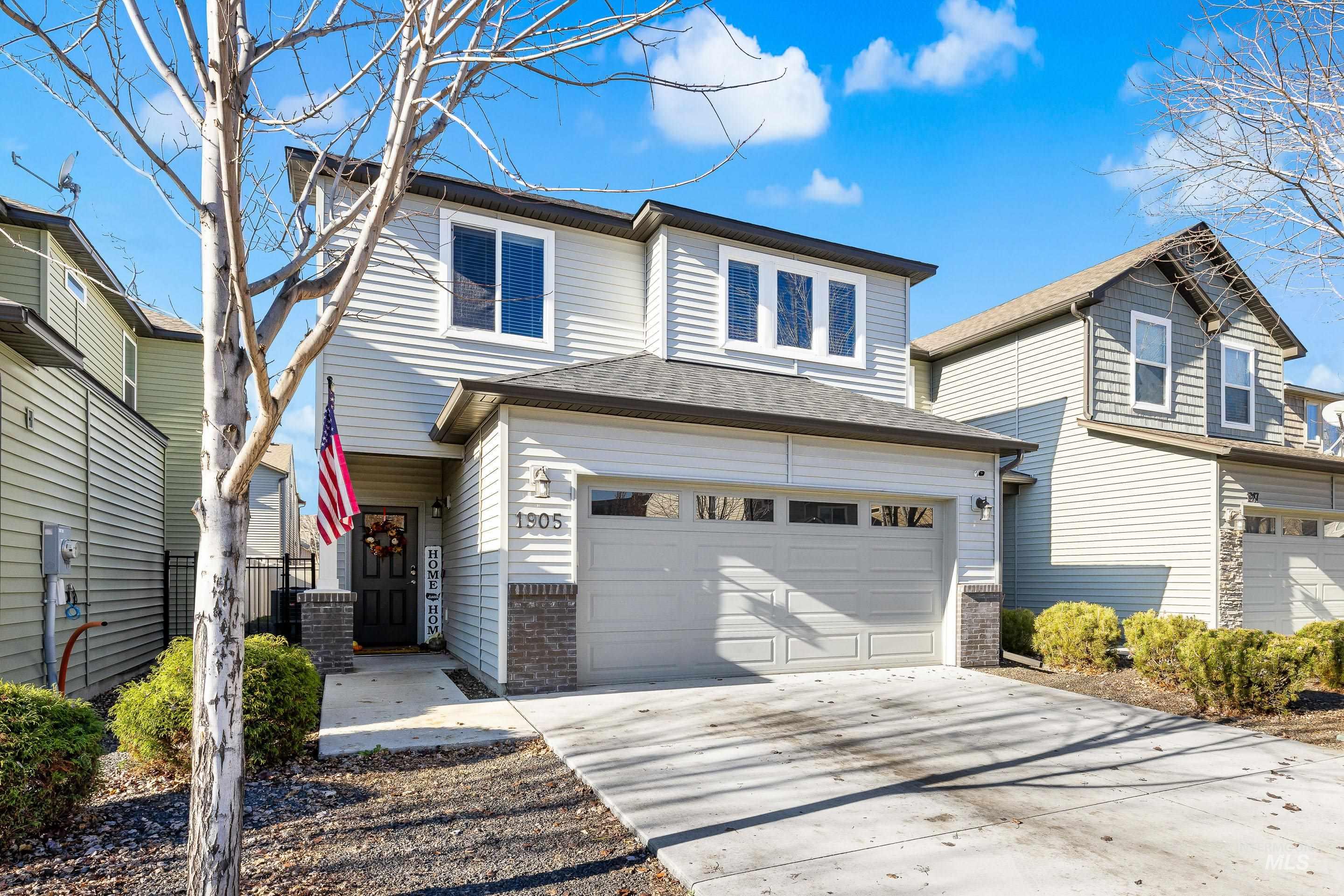 Traditional-style home featuring driveway, roof with shingles, brick siding, and a garage