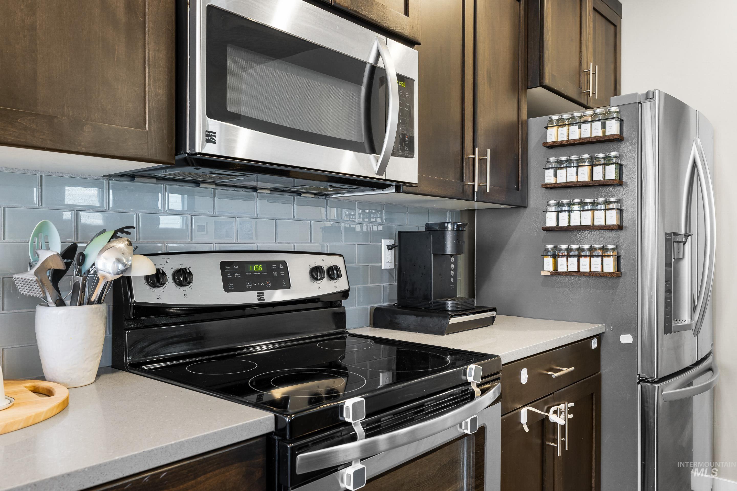 Kitchen with appliances with stainless steel finishes, decorative backsplash, and dark brown cabinets